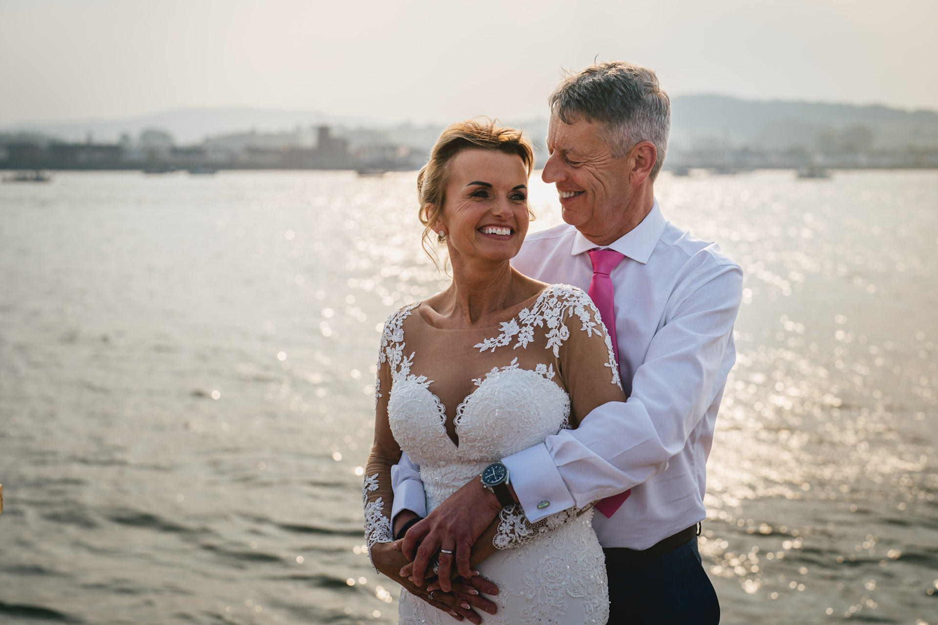 A bride and groom cuddling together on their wedding day on the River Exe Cafe