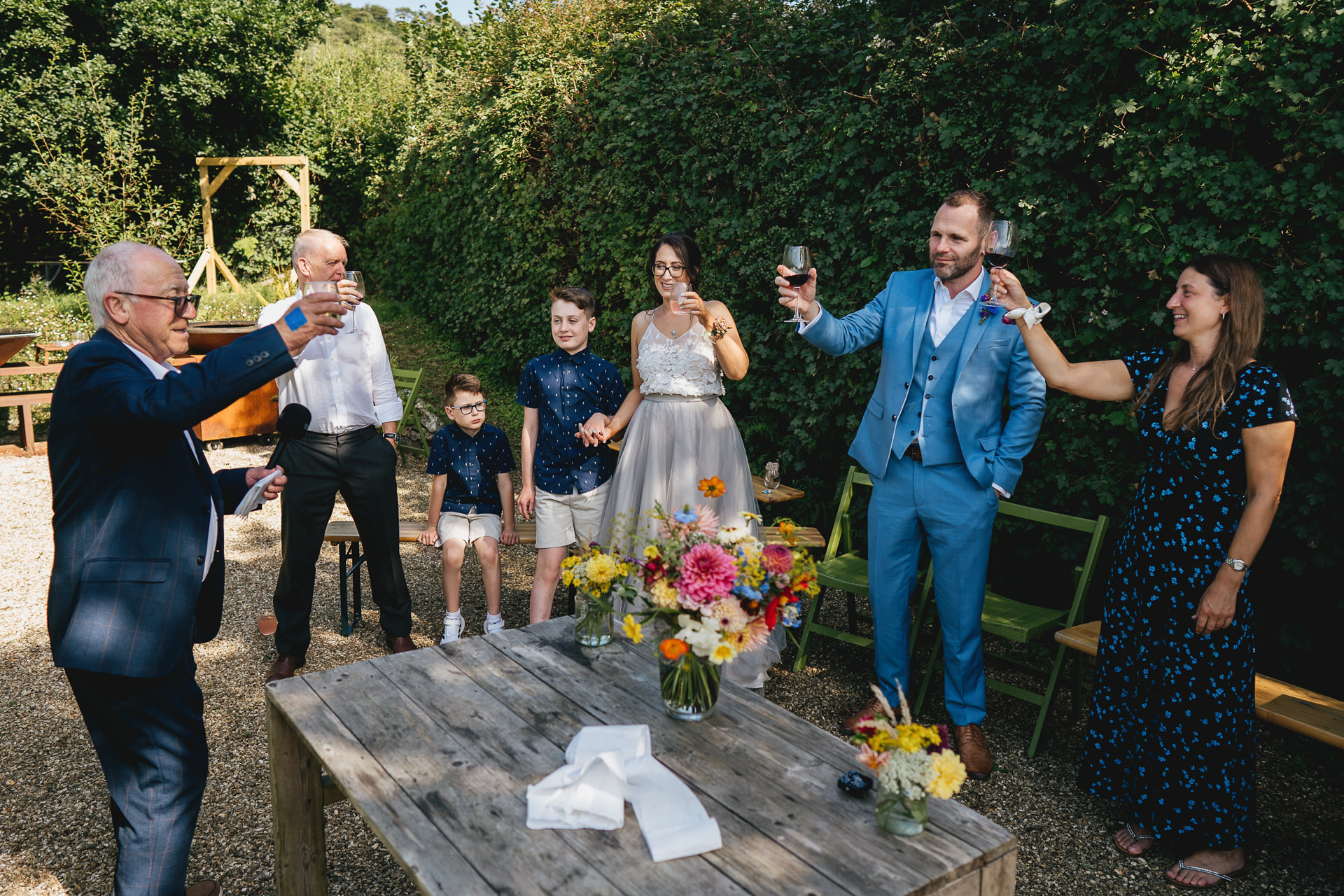 A wedding group during speeches in a garden setting