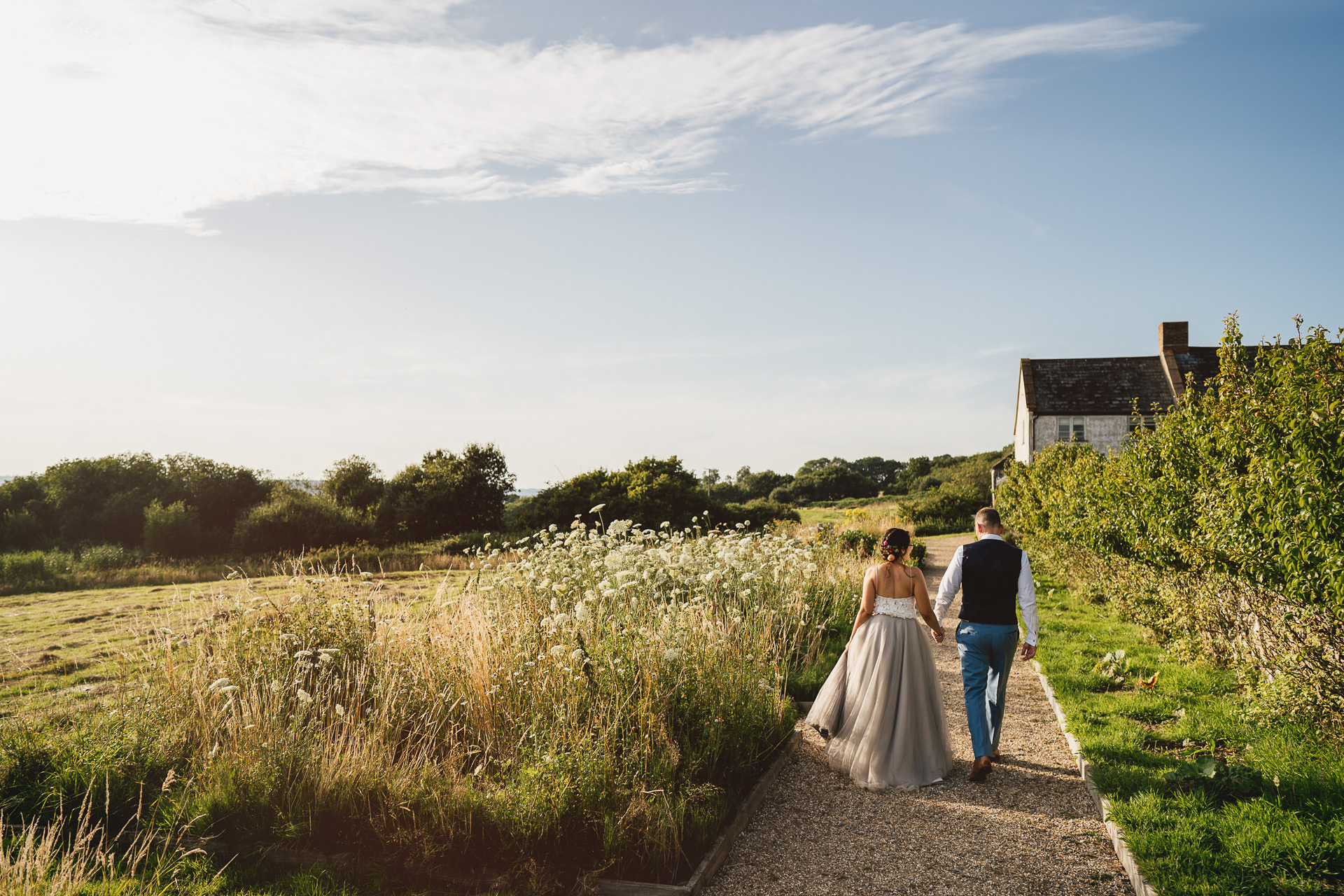 Bride and groom strolling along a path at River Cottage