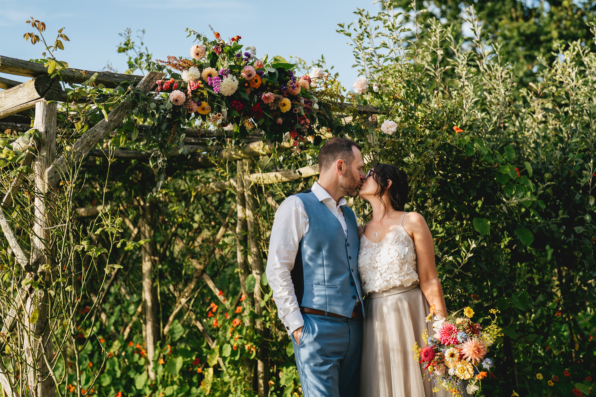 Bride and groom kissing in the kitchen garden after their elopement wedding at River Cottage