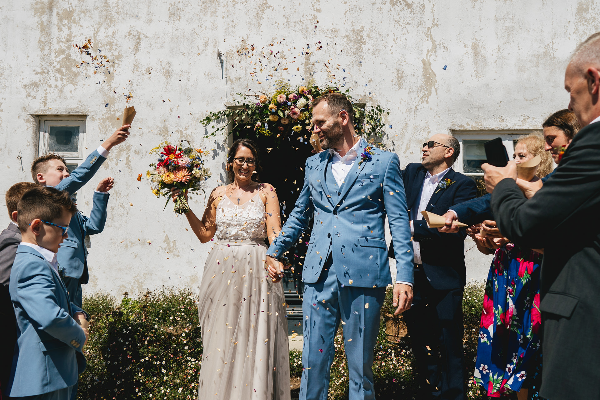 Guests throwing confetti over a bride and groom outside River Cottage farmhouse