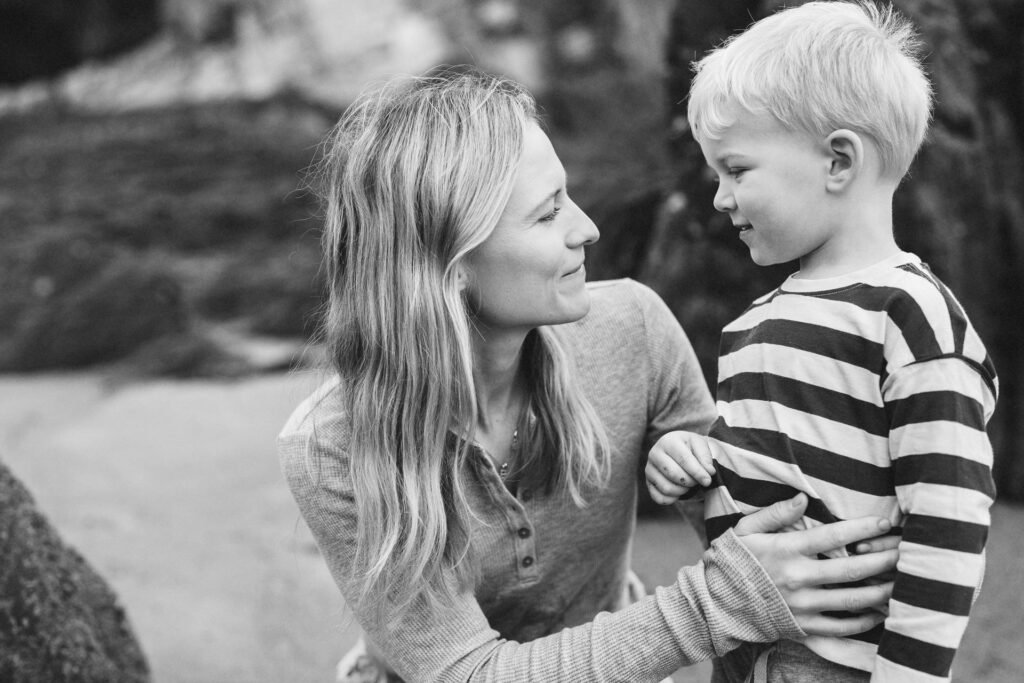 A mother and son smiling at each other on the beach during a family photography session in Devon