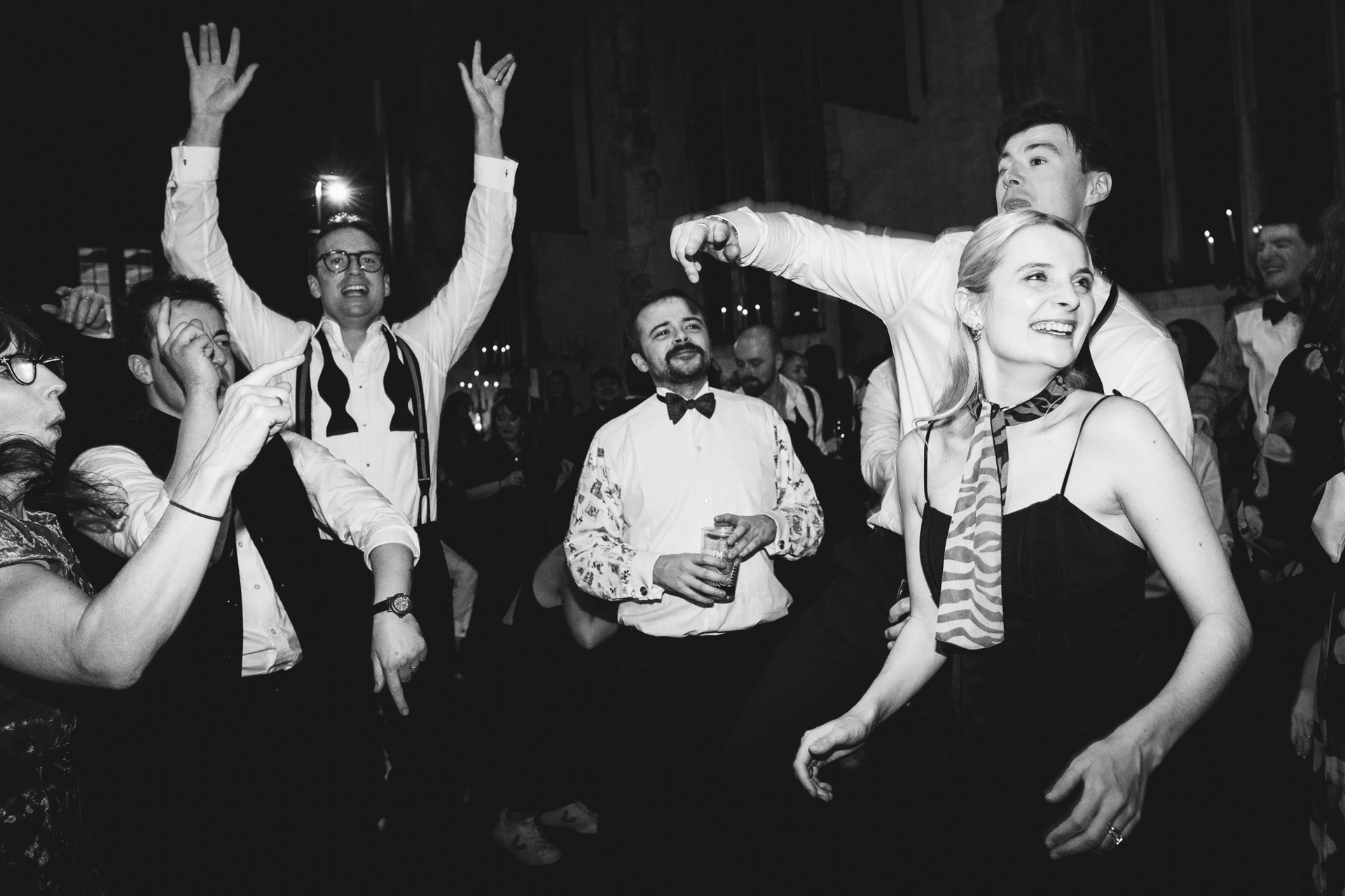 A bride and other wedding guests smiling on the dancefloor at Dartington Hall in Devon