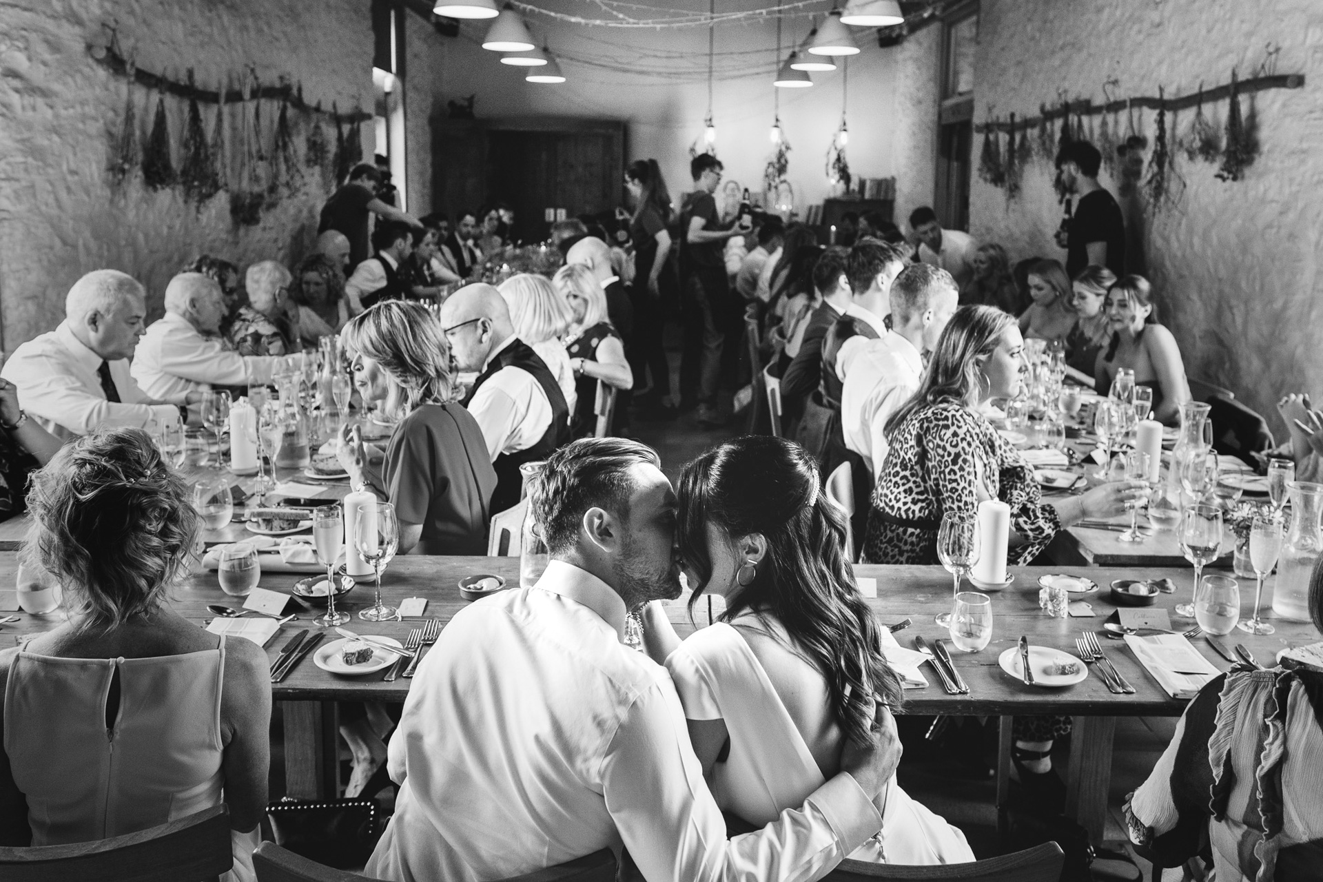 A bride and groom cuddling together during their wedding meal at River Cottage in Devon 