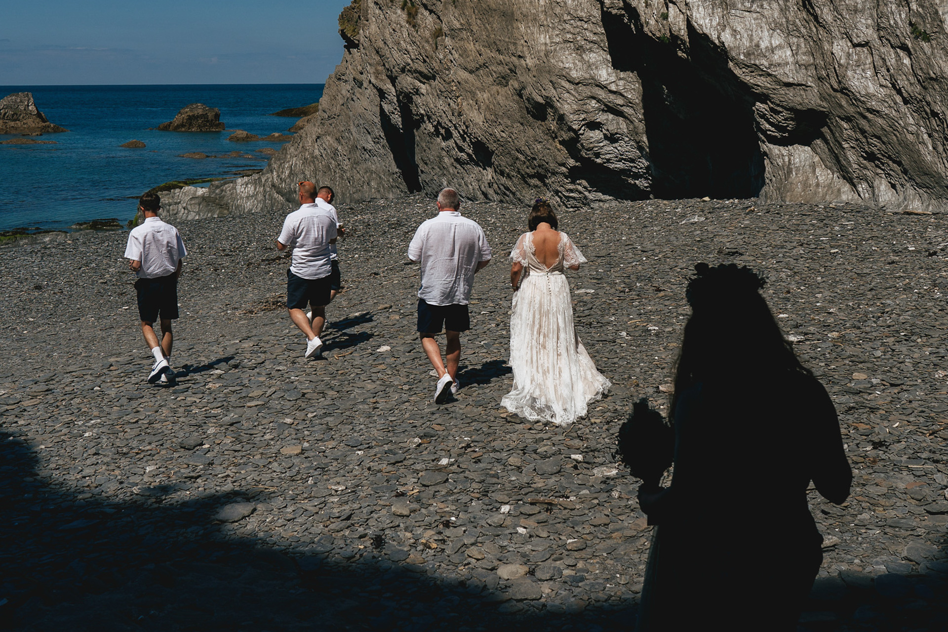 Wedding guests walking across the beach at Tunnels Beaches in North Devon