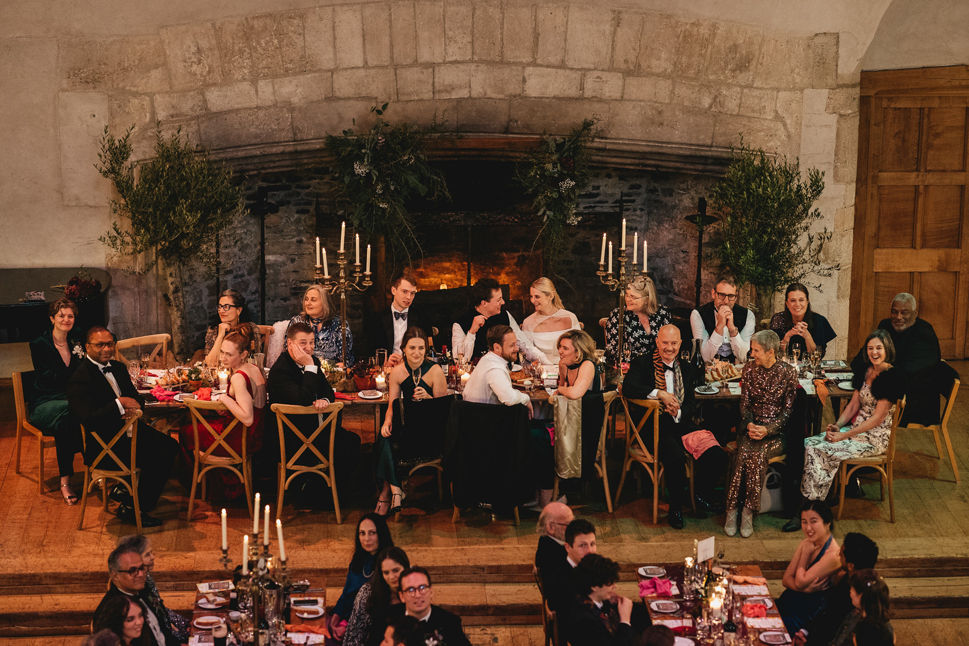 The top table at a wedding at Dartington Hall in Devon, with the bride and groom laughing together during speeches