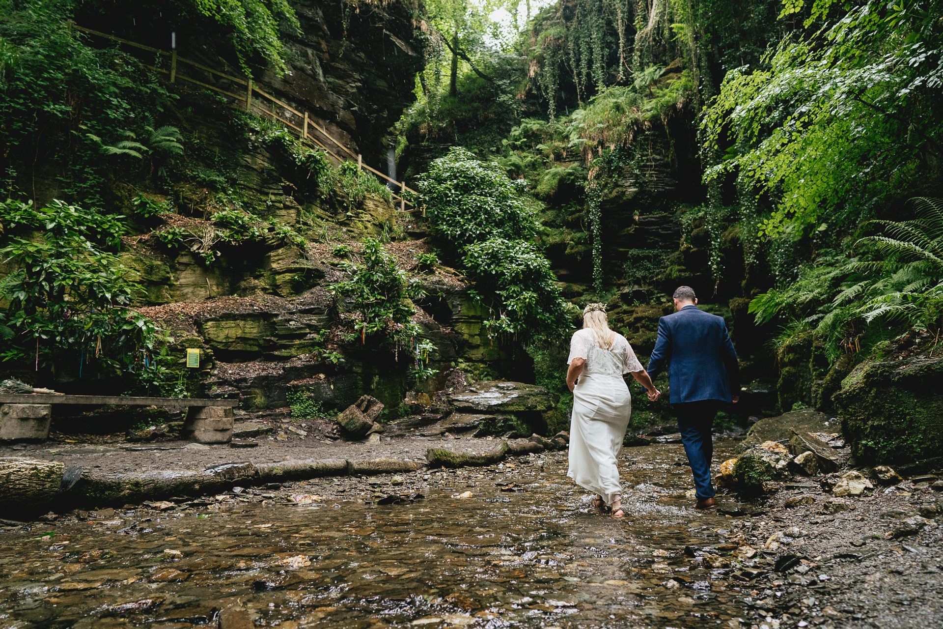 A couple walking through water on their elopement wedding day at St Nectan's Glen