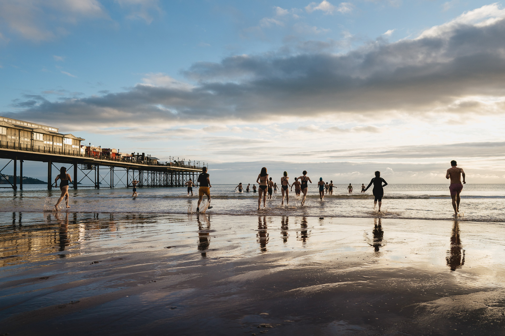 A large group of wedding guests running into the sea at Paignton in December