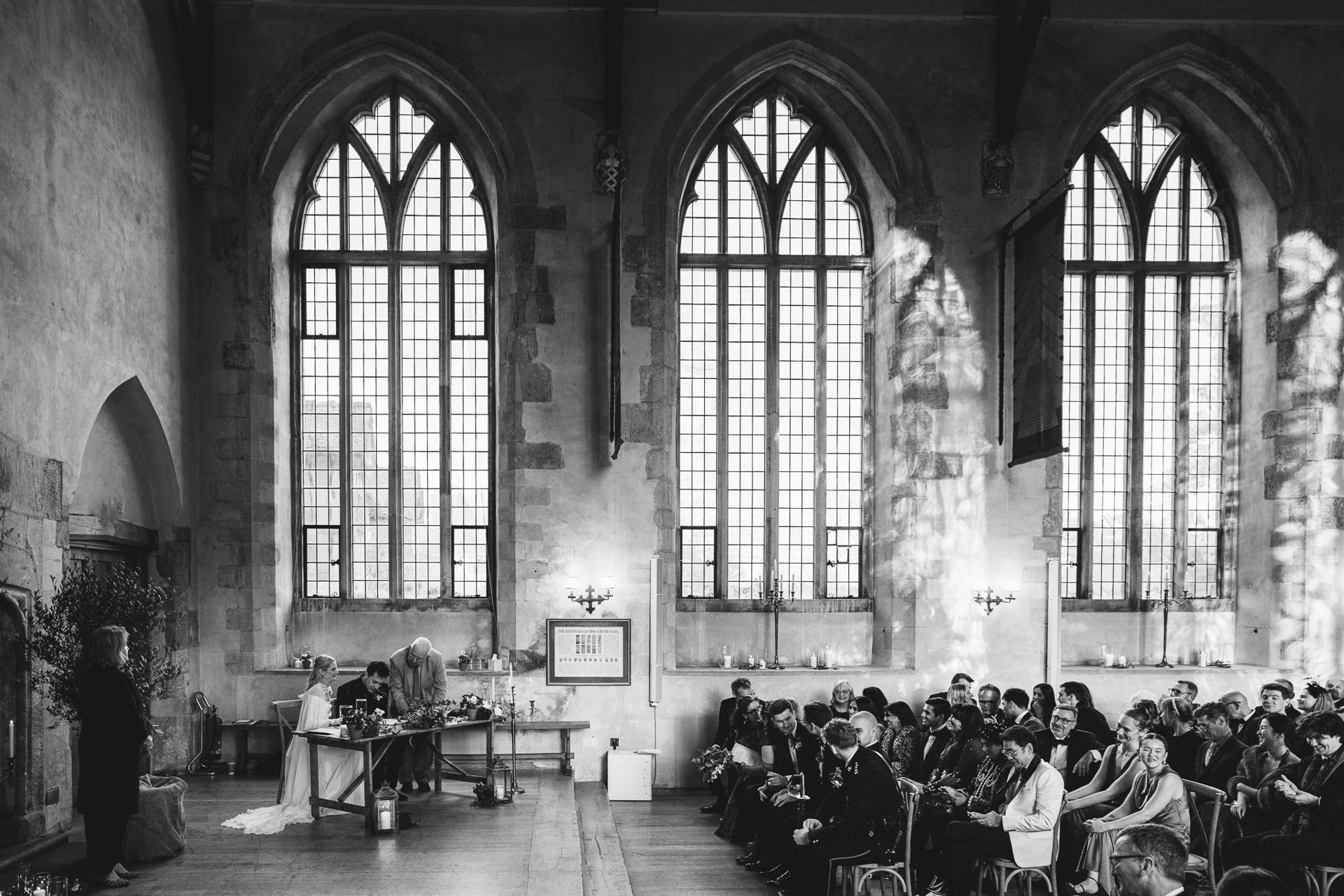 A bride and groom signing the register during their wedding ceremony at Dartington Hall in Devon