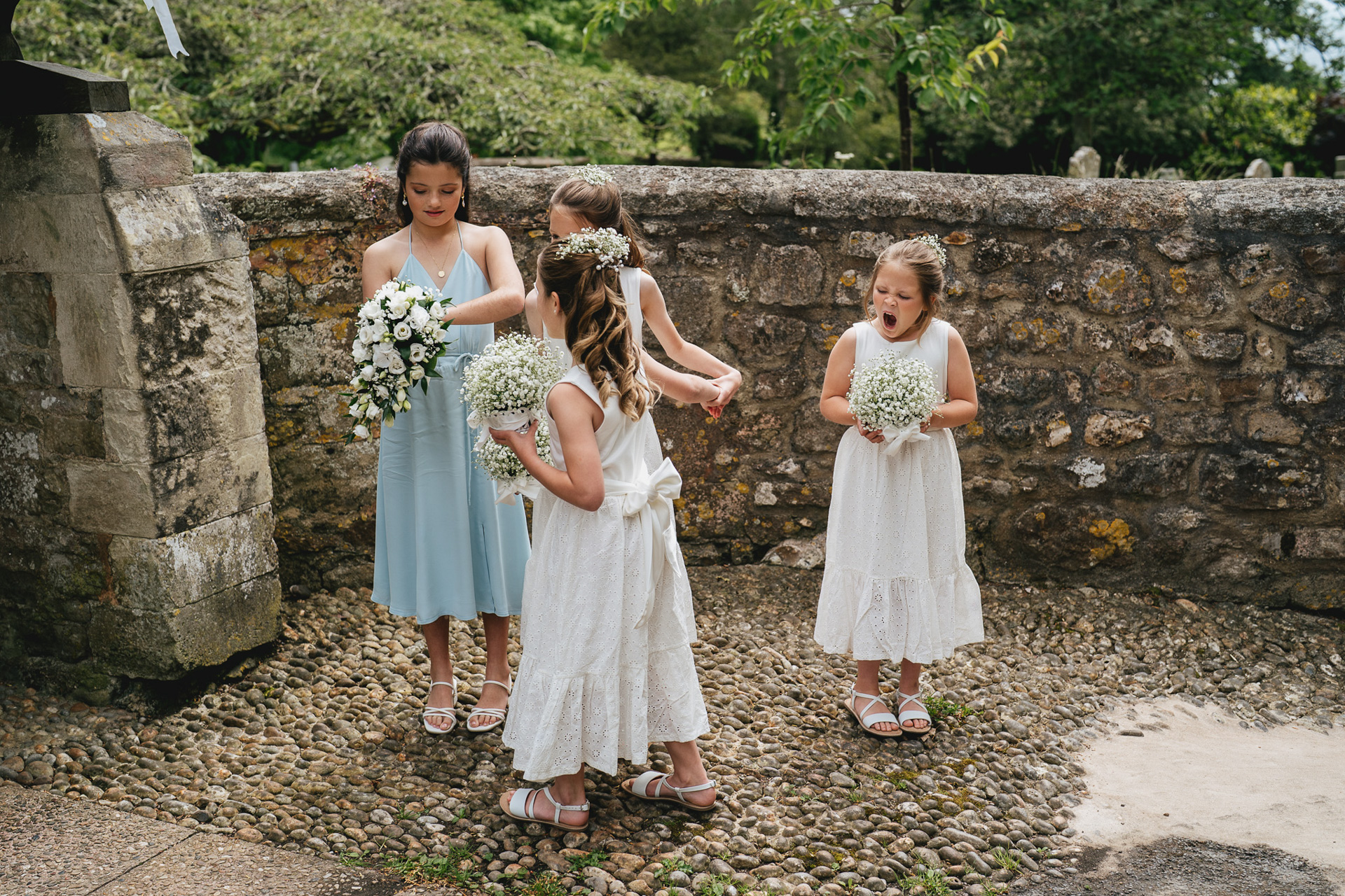 Flower girls waiting outside the church in Salcombe Regis, Devon, with one of them yawning widely