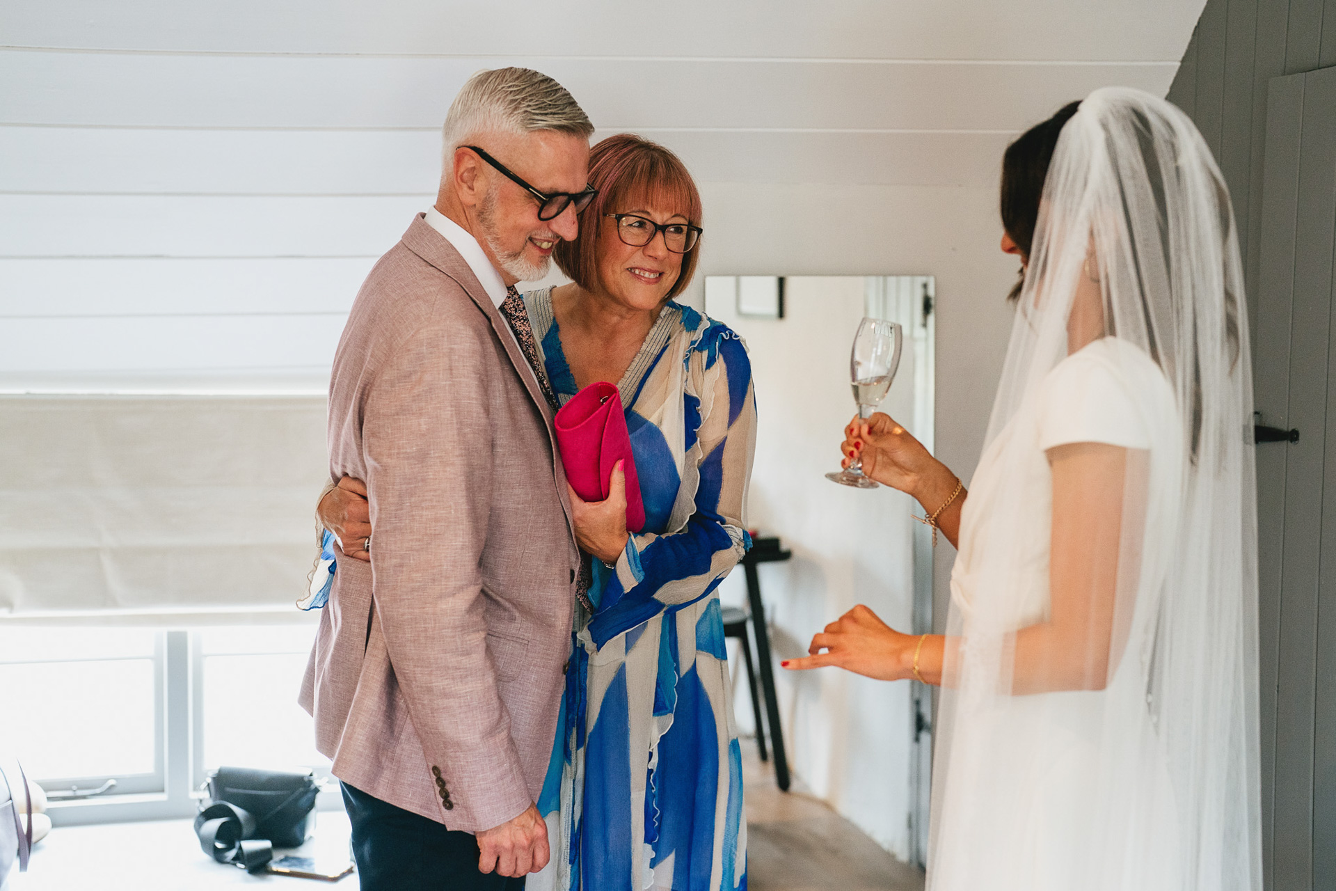 A bride's parents looking proudly at her in her wedding dress