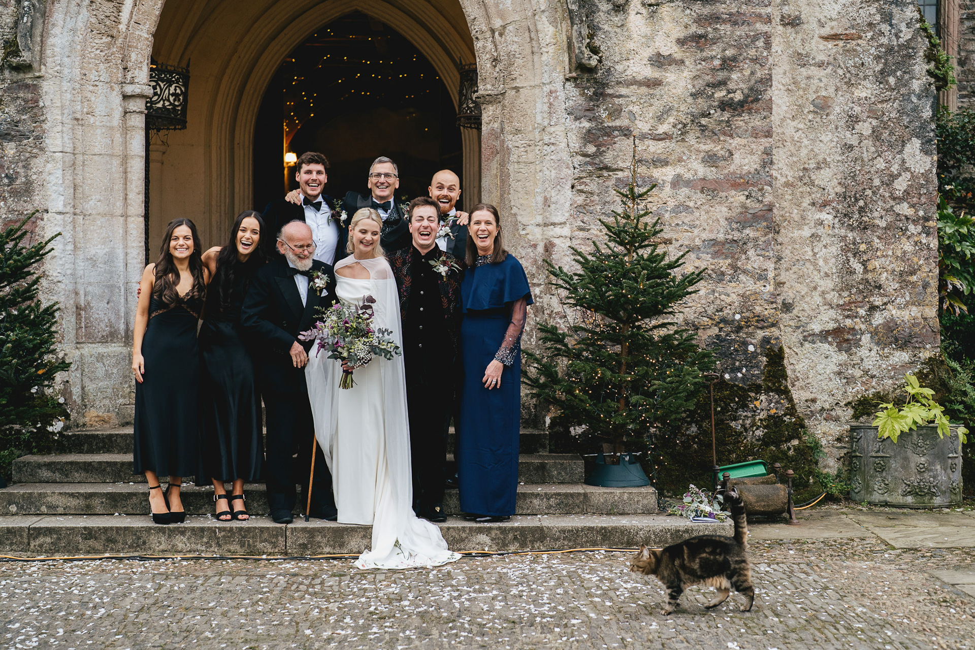 A cat walking through a wedding group photo at Dartington Hall