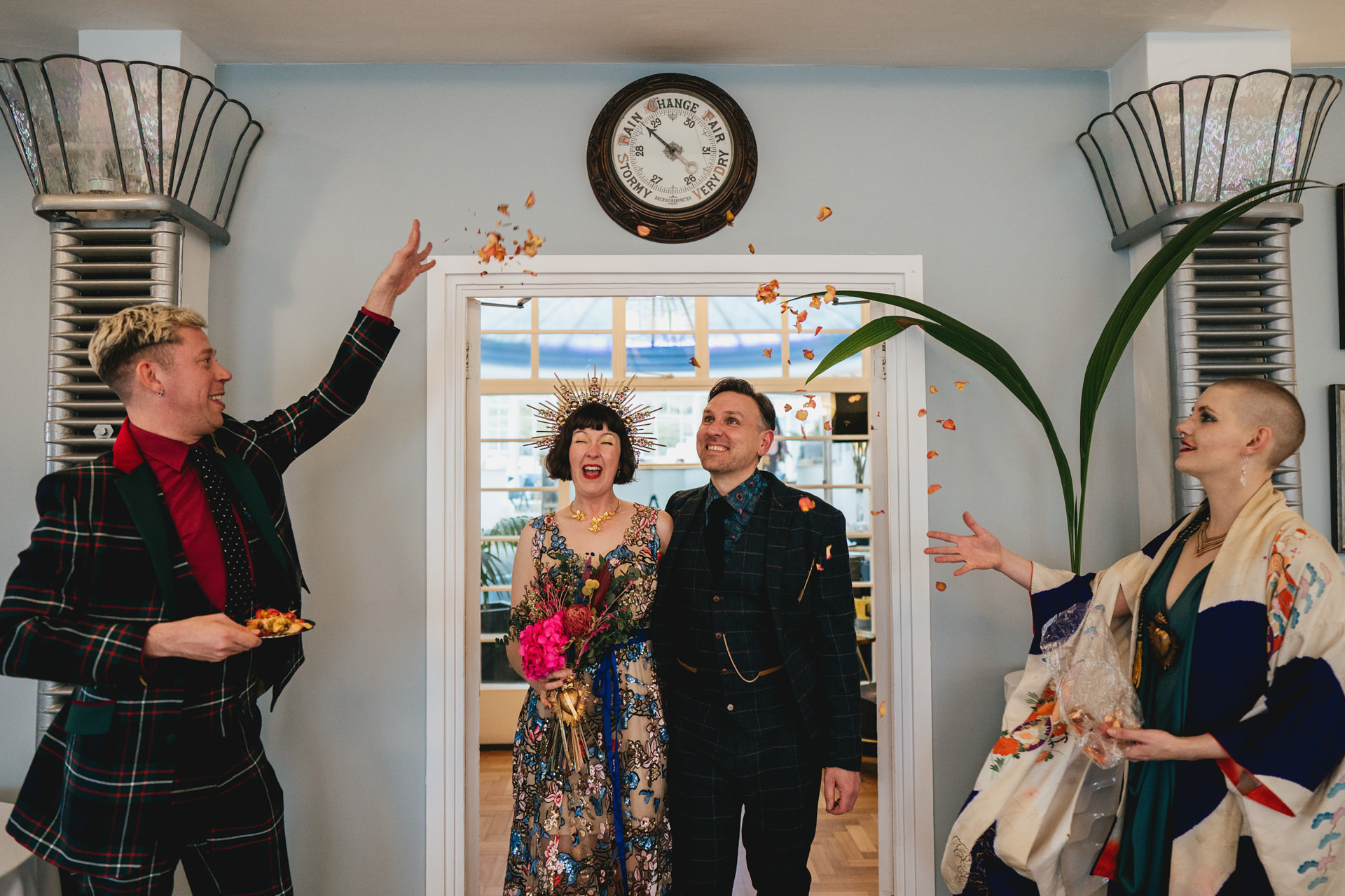 Two guests throwing confetti over a bride and groom at their Burgh Island elopement wedding