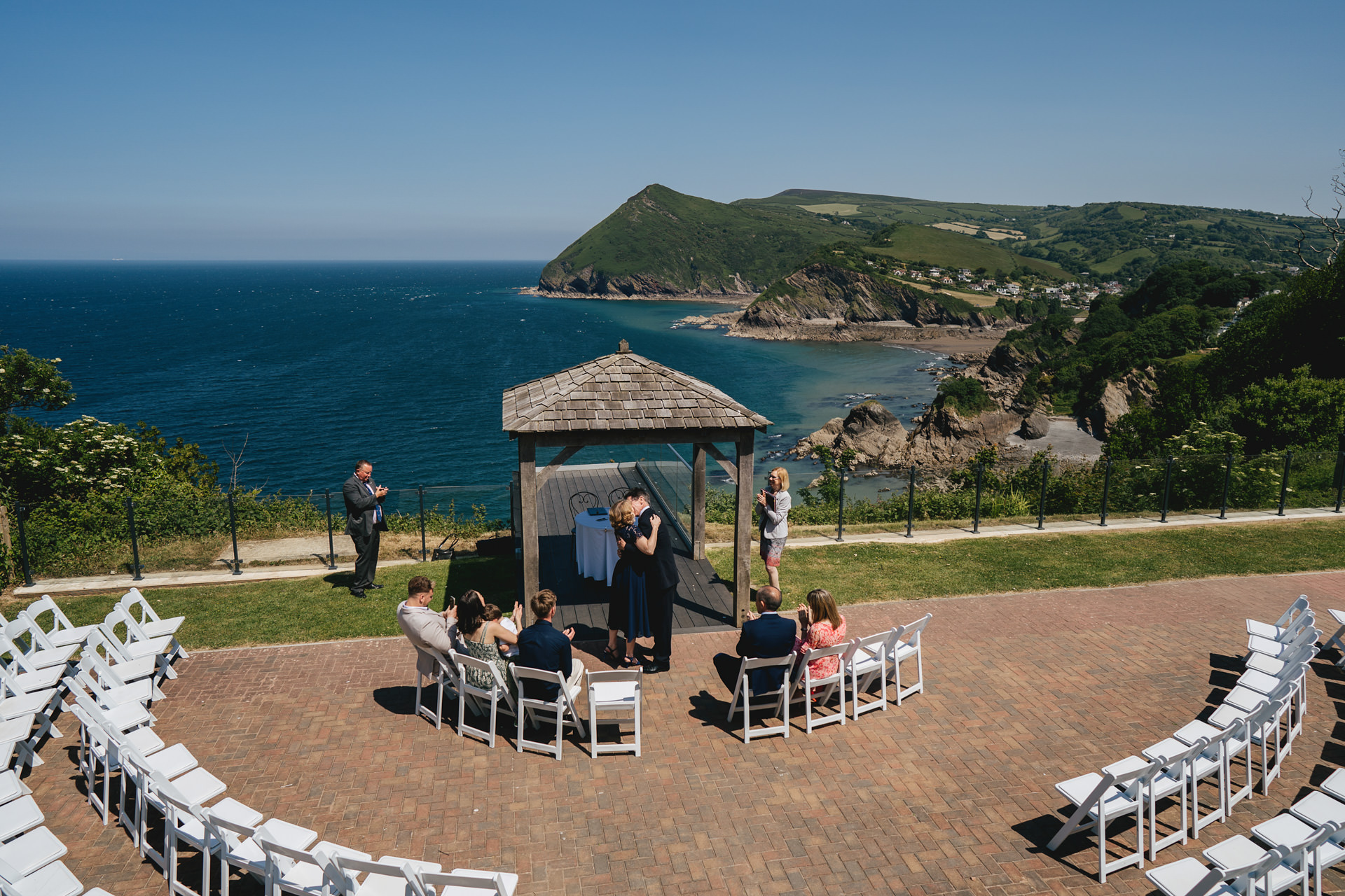 Bride and groom kiss at a tiny elopement at Sandy Cove in North Devon with a spectacular view across blue seas behind them