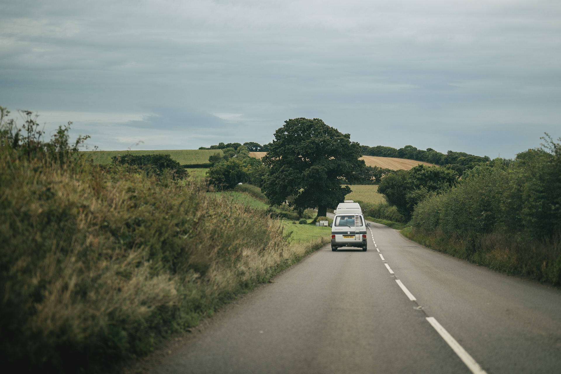 A campervan driving across Devon hills with a bride and groom after a wedding ceremony