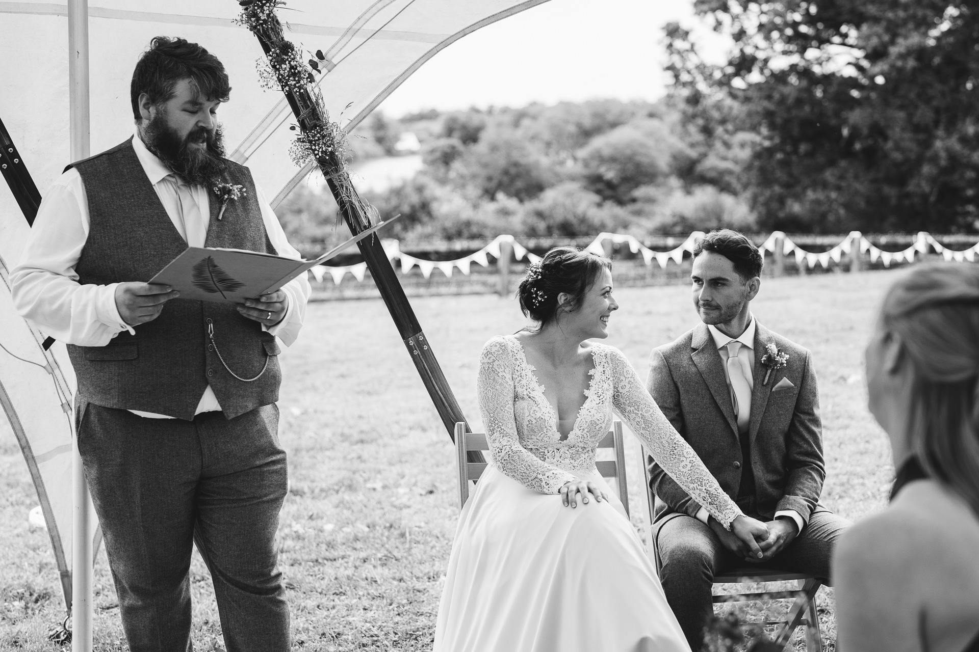 A bride and groom smiling at each other during a village hall wedding ceremony
