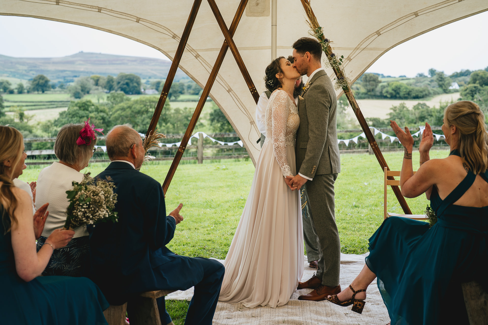Bride and groom kissing during a wedding ceremony in a stretch tent at a Dartmoor village hall