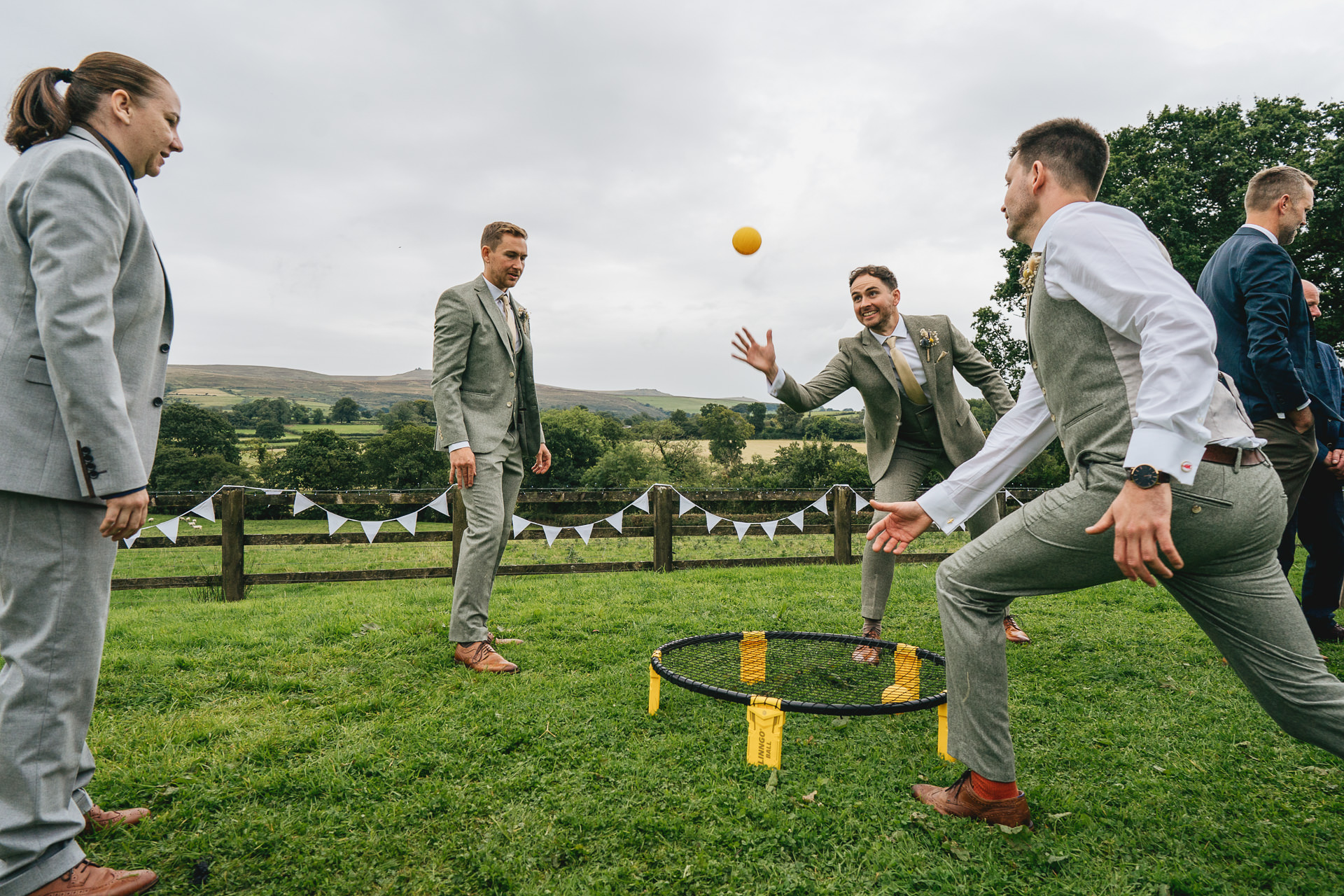 Groom and groomsmen playing ball games at a village hall wedding celebration
