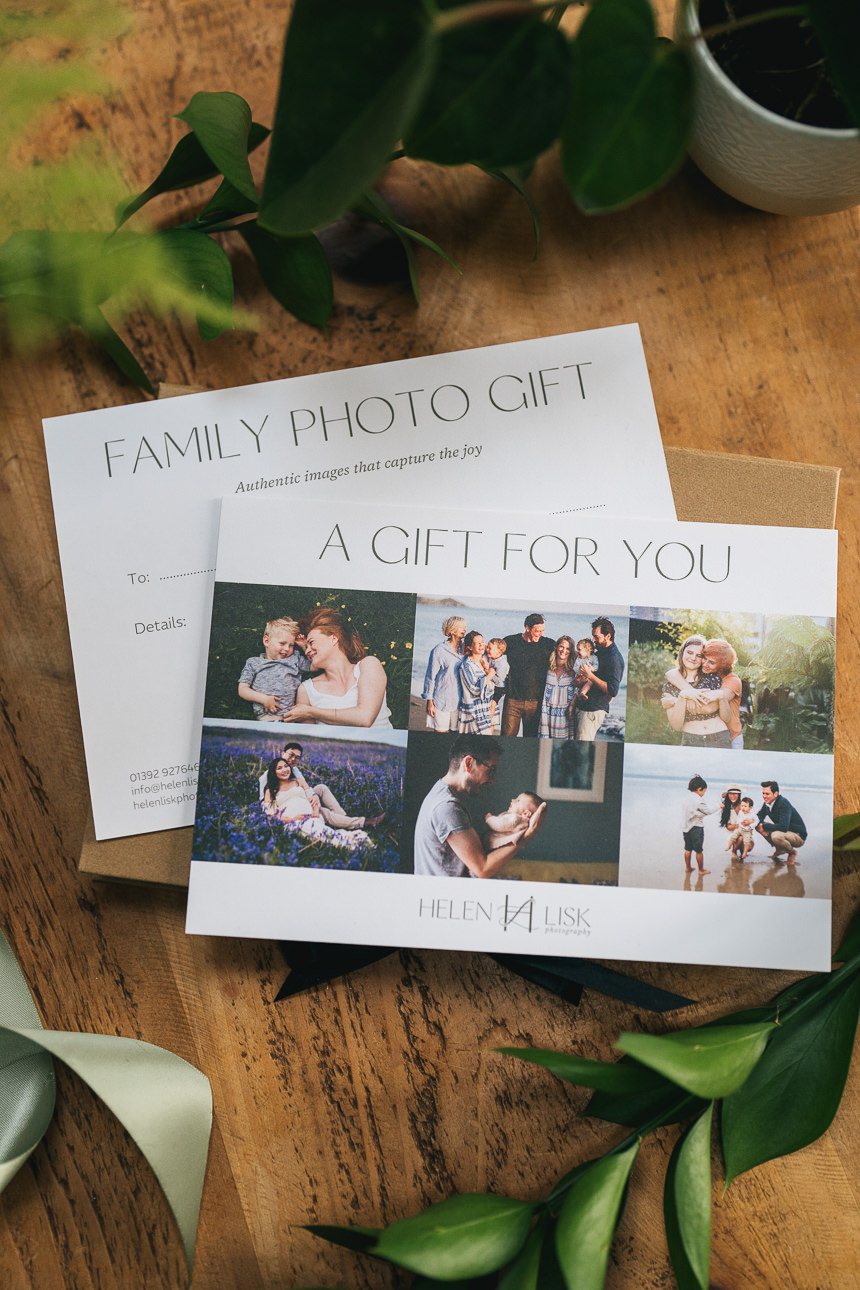 A family photography gift voucher in a presentation box, with green leaves and ribbon around it