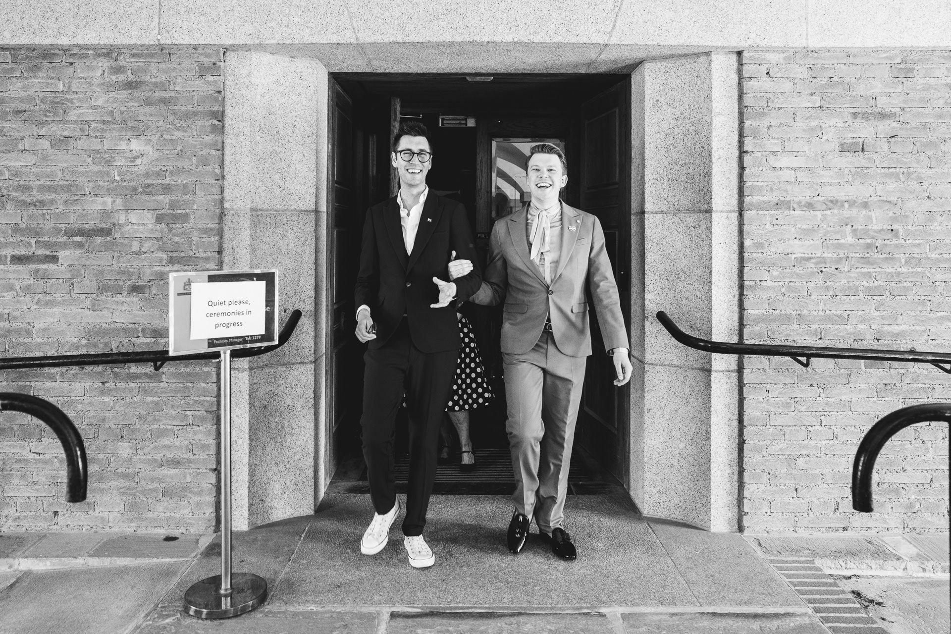Just married grooms leaving their wedding ceremony arm in arm and smiling