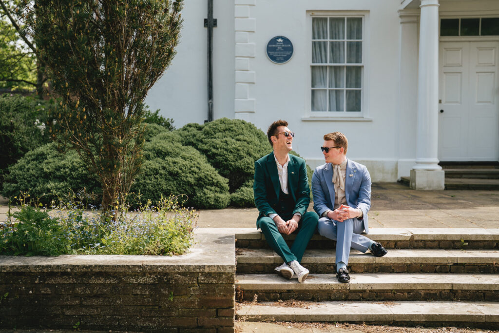Two men sitting together on a step at County Hall Exeter after their elopement wedding ceremony