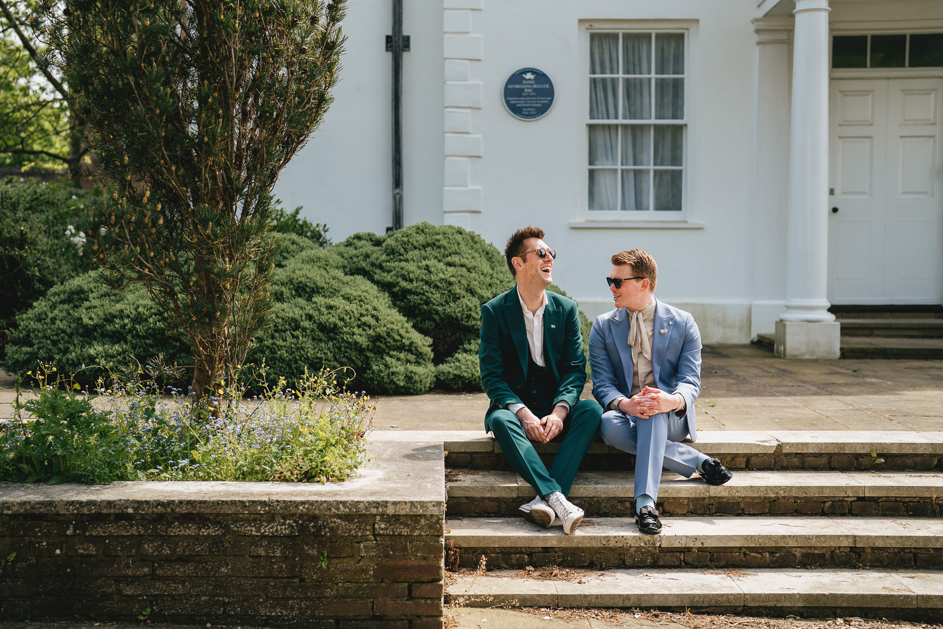 Two men sitting together on a step at County Hall Exeter after their elopement wedding ceremony