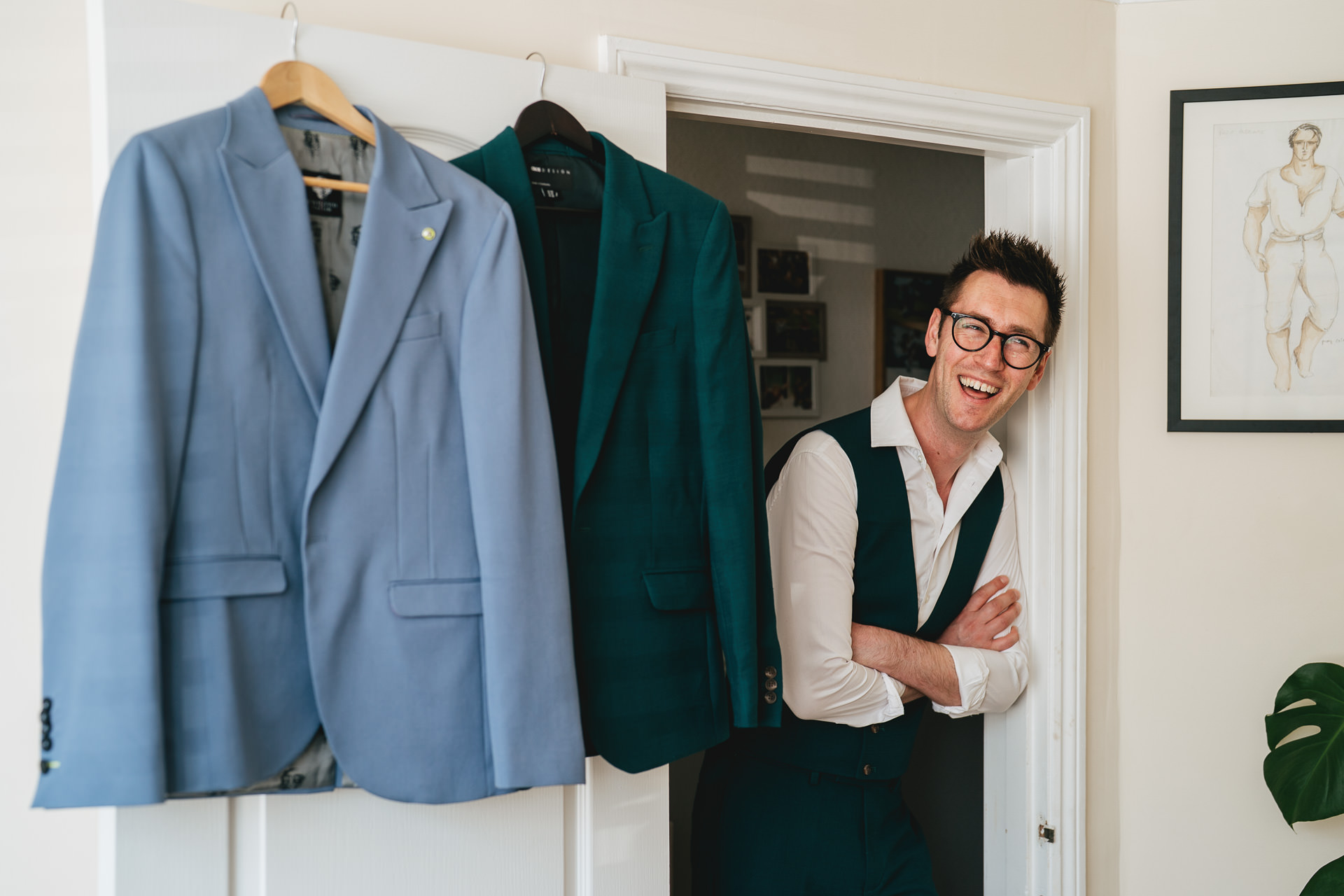 A groom leaning on a doorframe and laughing in his Exeter home, ahead of his elopement wedding