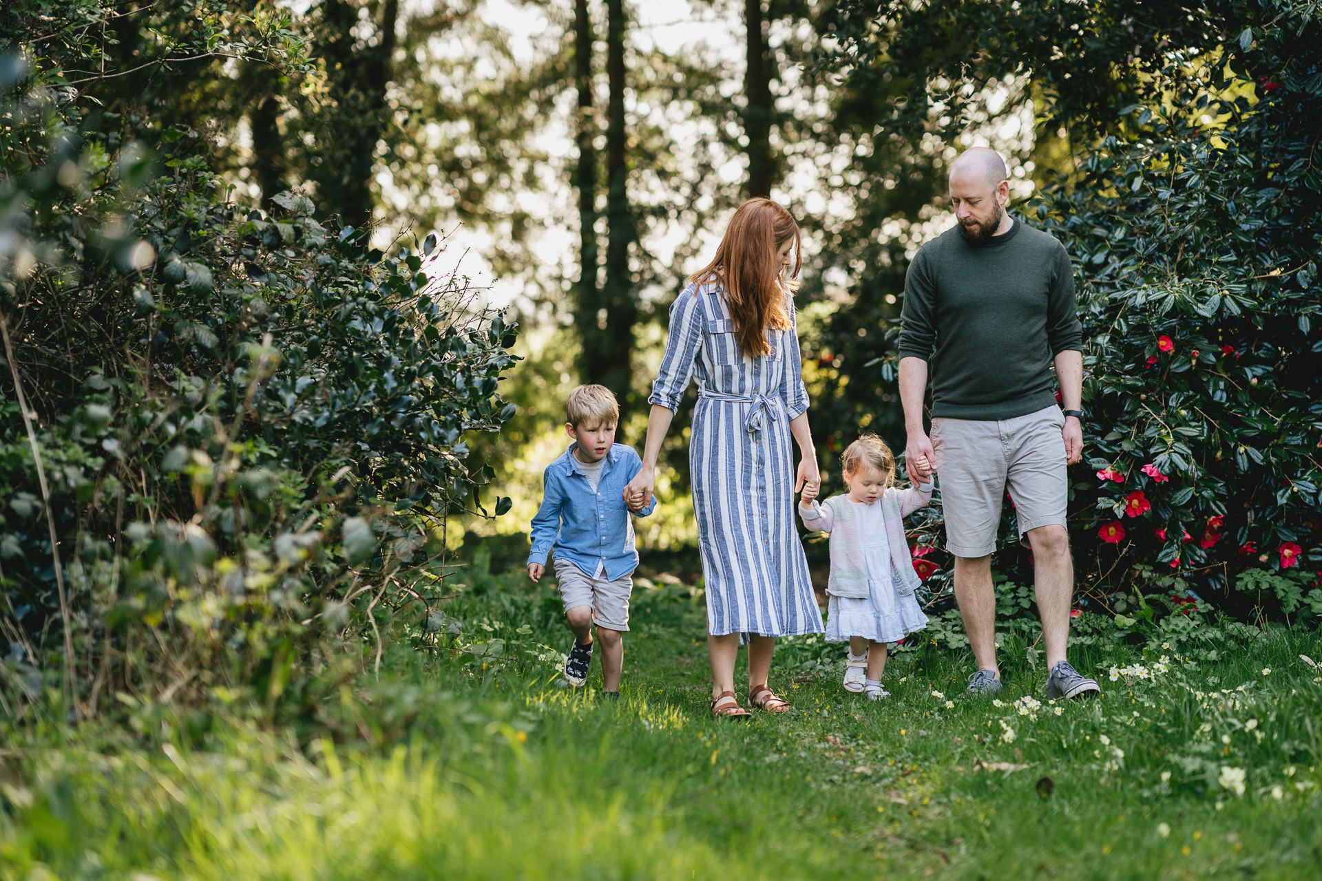Two parents walking holding hands with young children for a photography session near Exeter