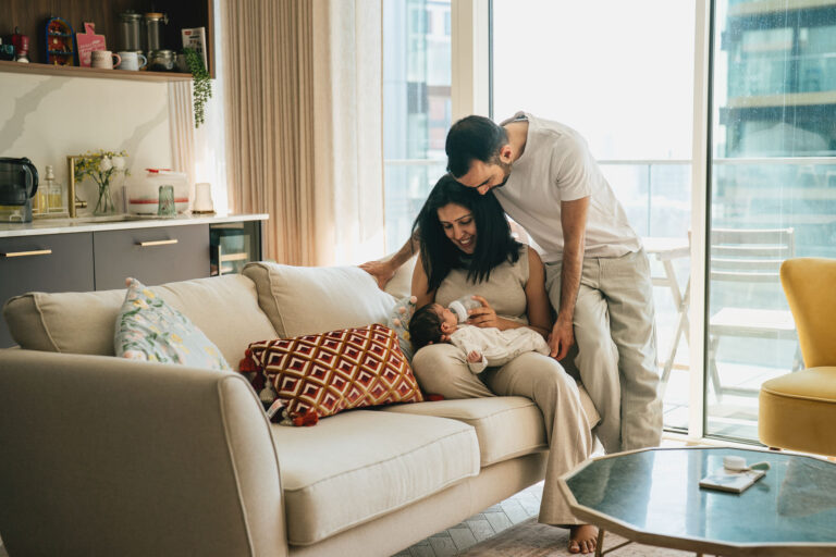 A relaxed image of two parents together with their newborn baby during a photography session at their home