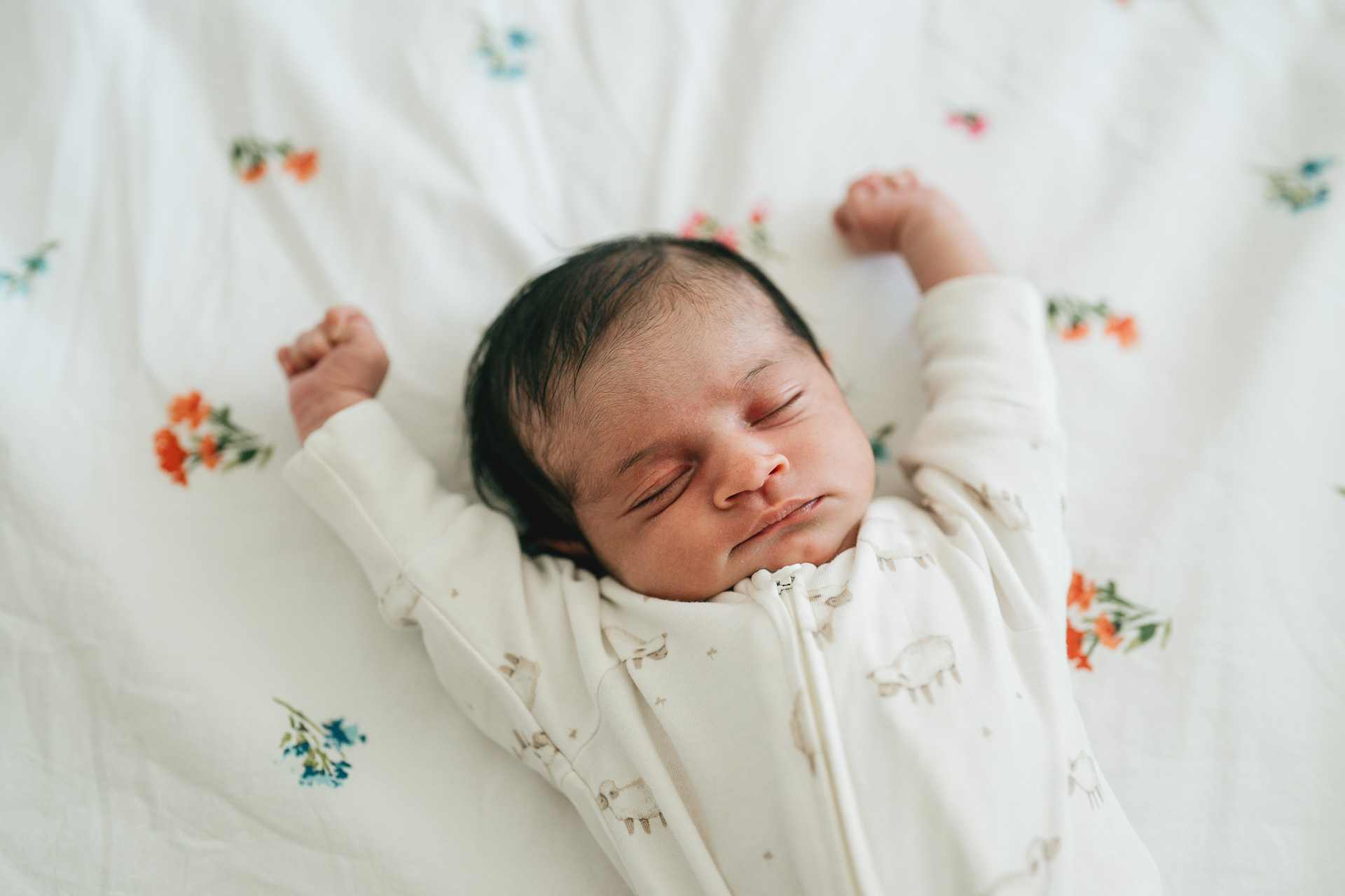 A newborn baby lying on a patterned bedspread