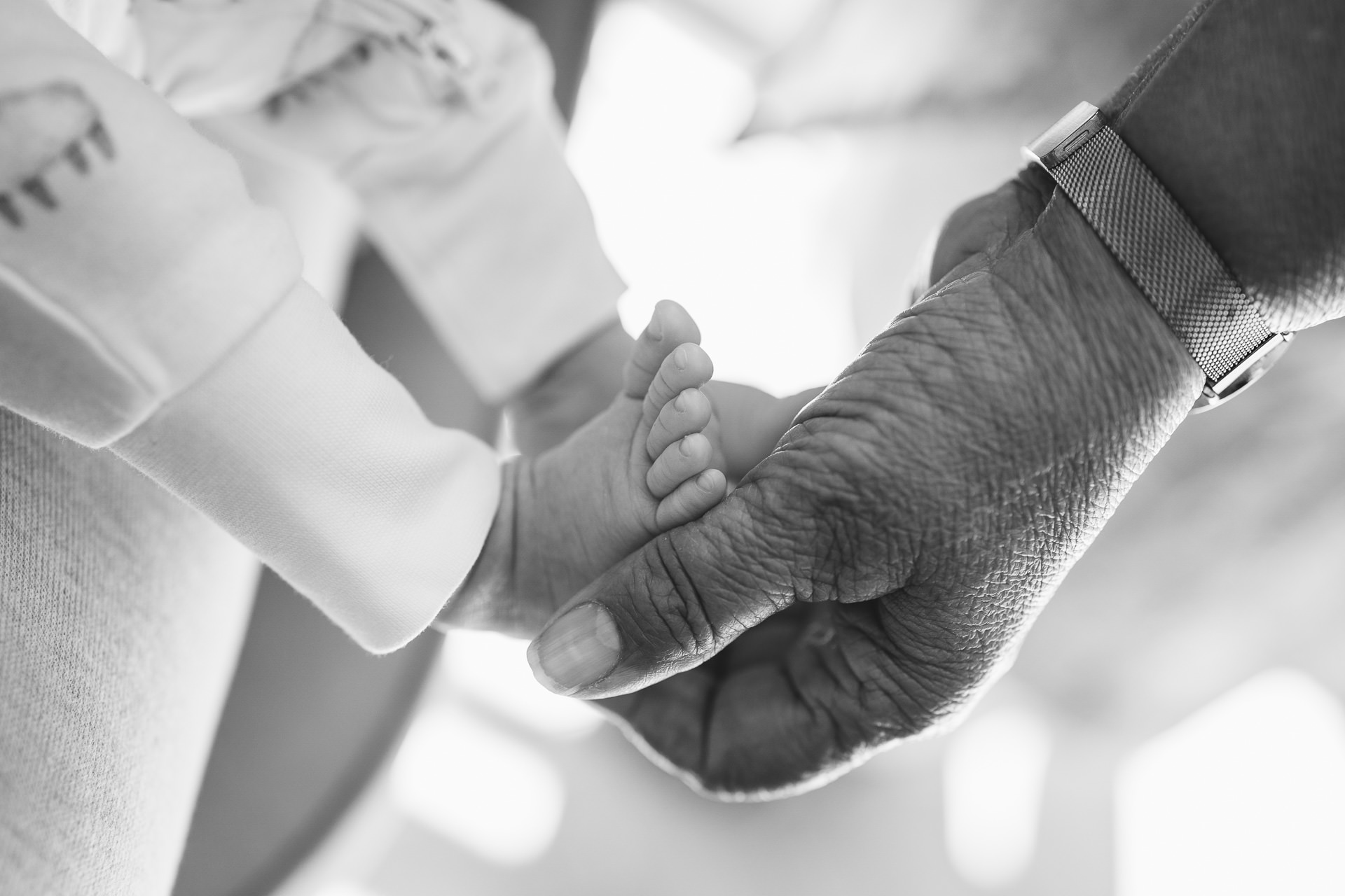 A grandmother's hand holding a newborn baby's foot