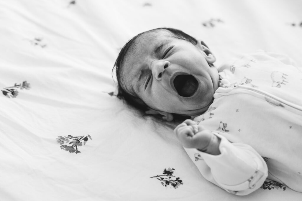A newborn baby yawning during a photography session at home