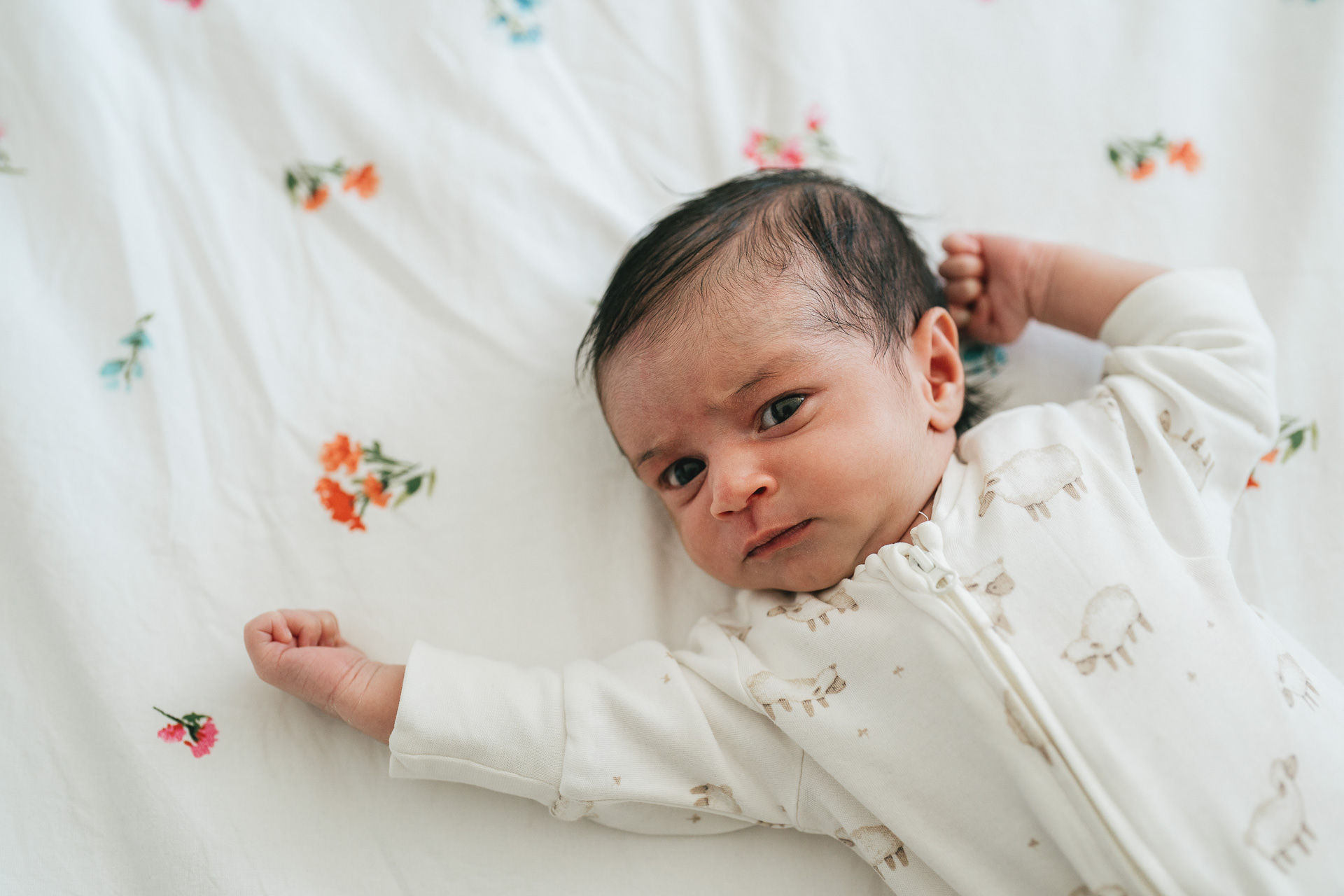 A newborn baby lying on a patterned bedspread