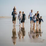 A group having a family photography session on the beach in Devon, with evening sunlight and reflections on the wet sand