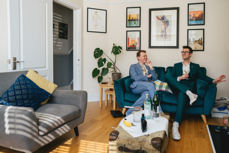 Two grooms drinking martinis in their stylish home, ahead of their wedding ceremony in Exeter