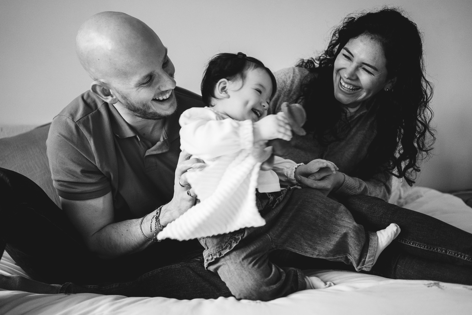 Parents playing together with a baby girl during a photo session at home in North Devon