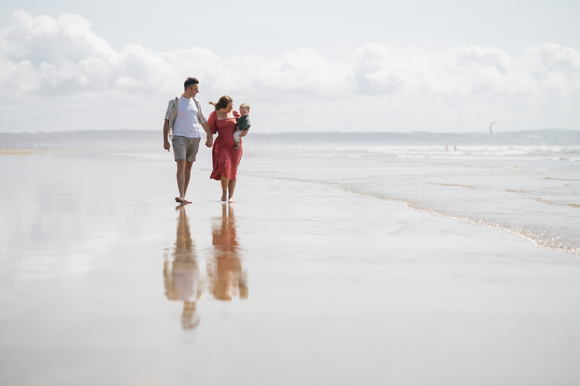 Two parents with a young baby walking on the beach at Saunton Sands in North Devon
