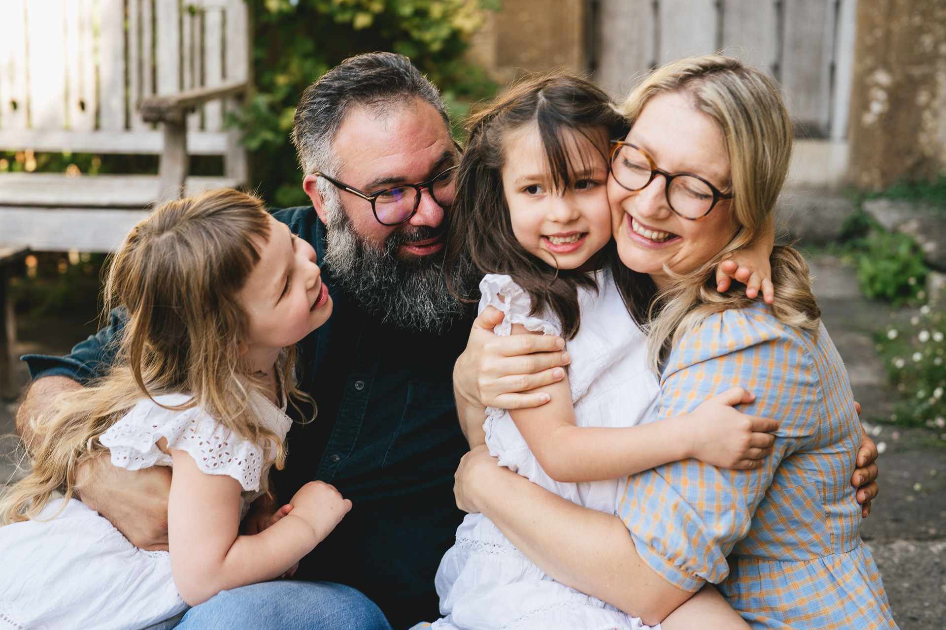 A relaxed family group photo with two young girls cuddling and laughing with their parents in Symondsbury in Dorset. 