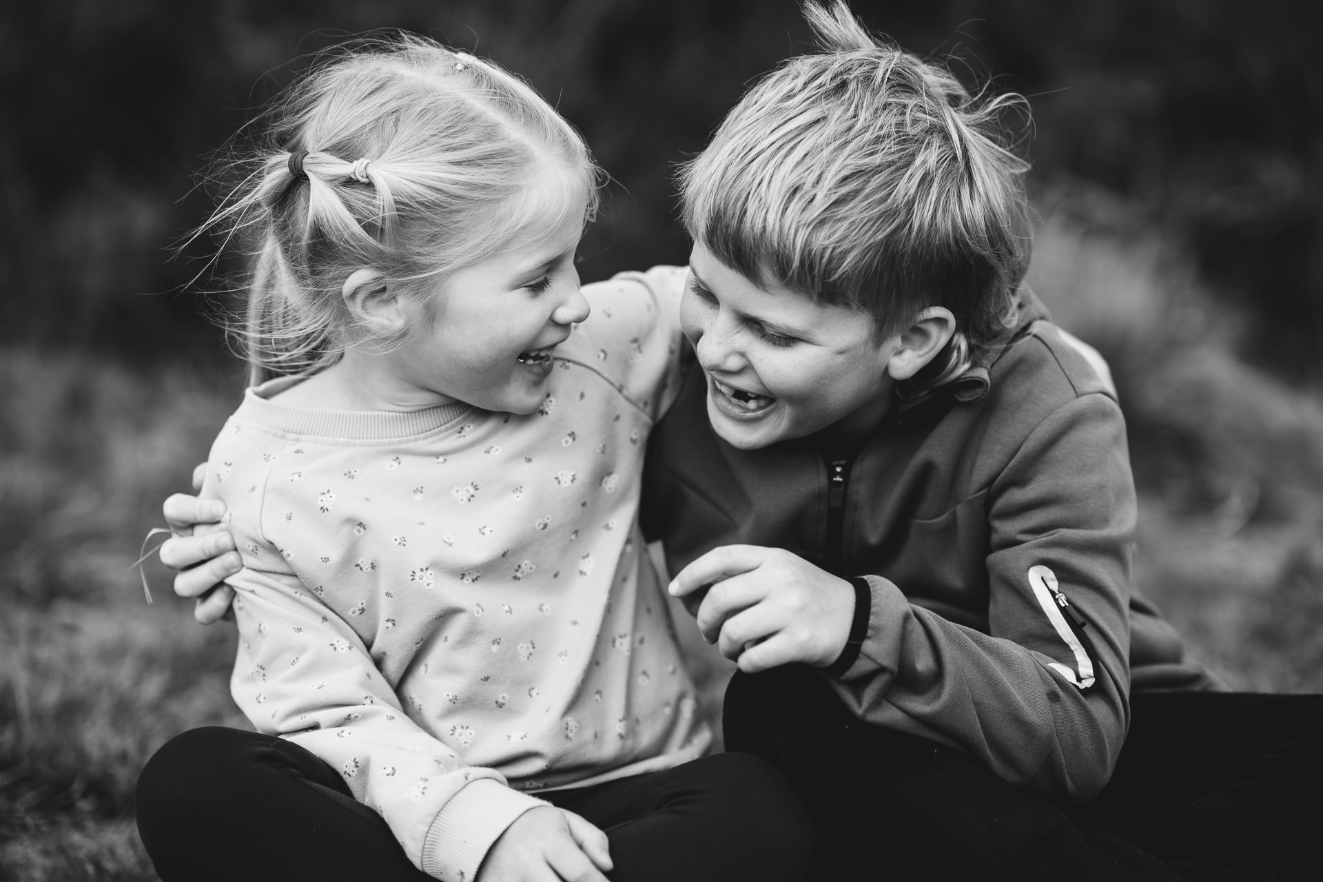 A brother and sister arm in arm and laughing together during a gift voucher family photography session near Exeter. 