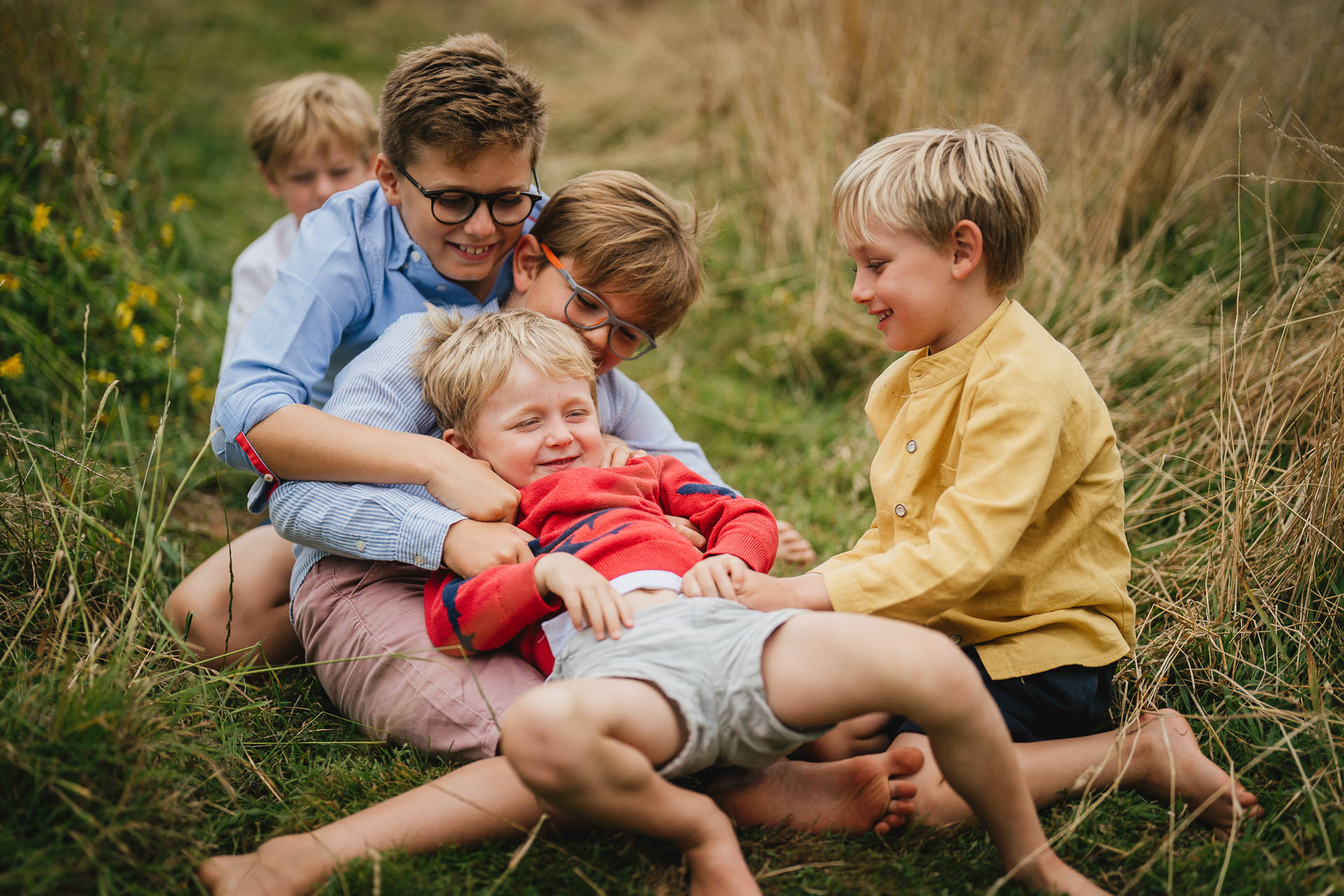 A group of cousins playing together in a garden during a family photography session