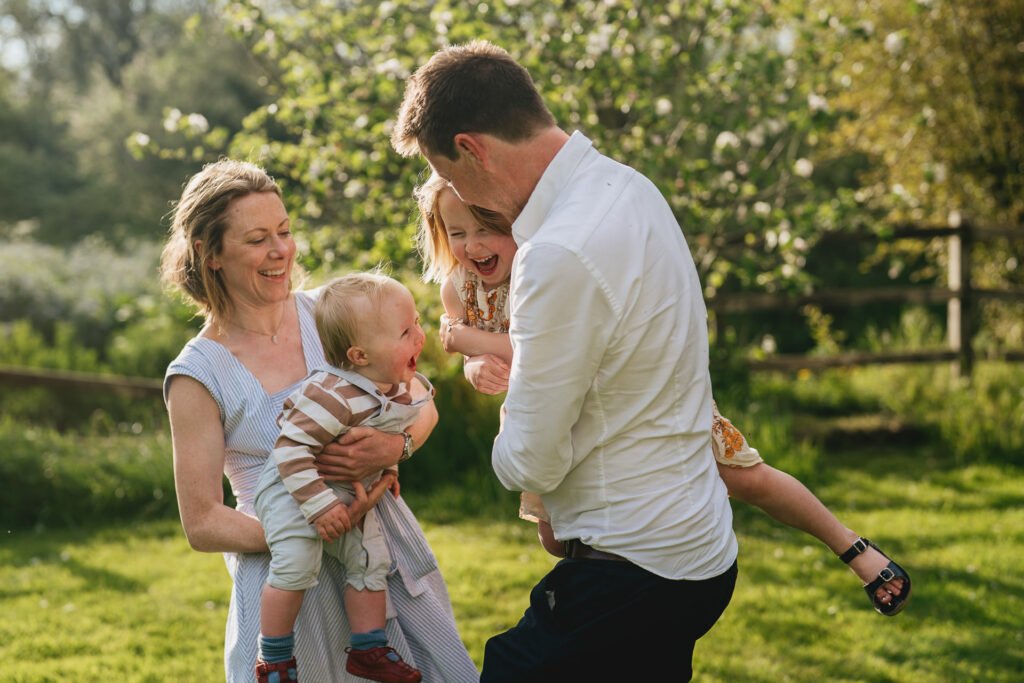 A family playing together in the garden and laughing during a family photography session