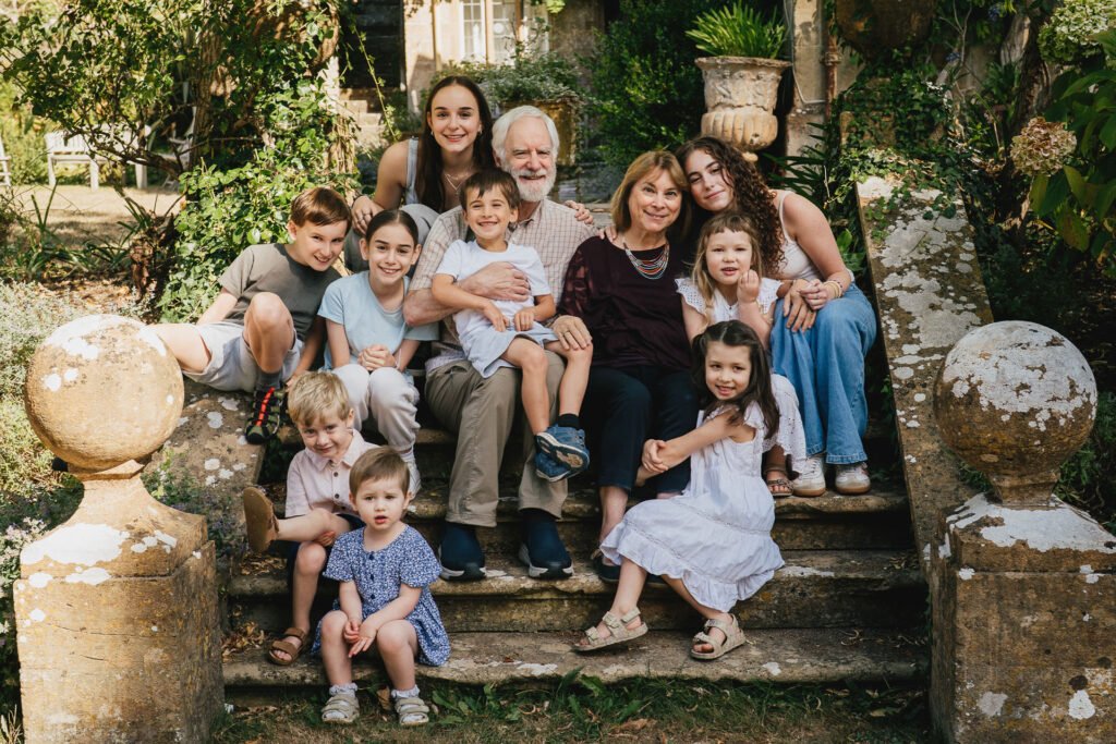 Relaxed family group photo with grandparents sitting on steps with lots of grandchildren from an extended family photography session at Symondsbury in Dorset
