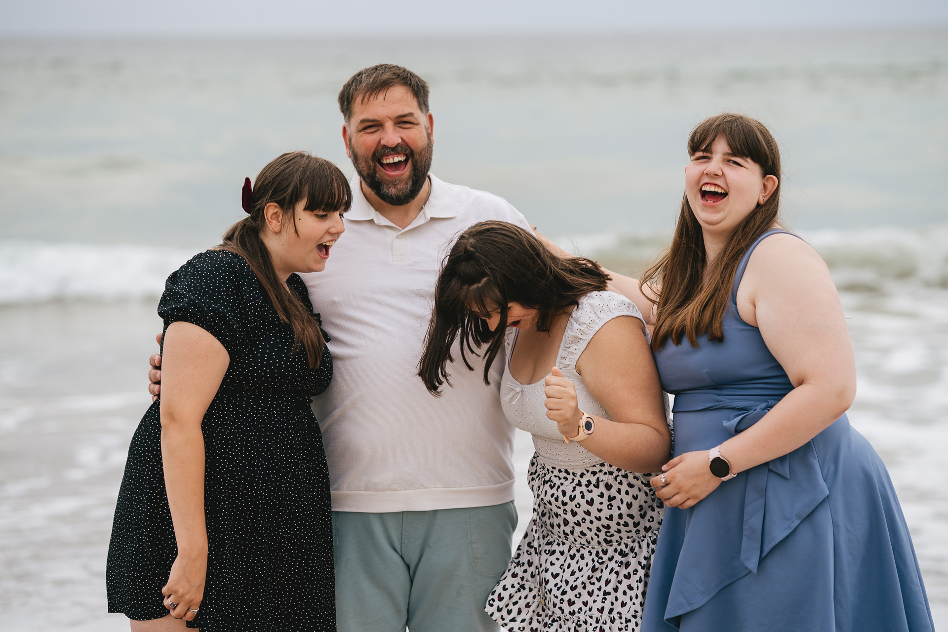 A father with three teenage daughters on the beach in Cornwall