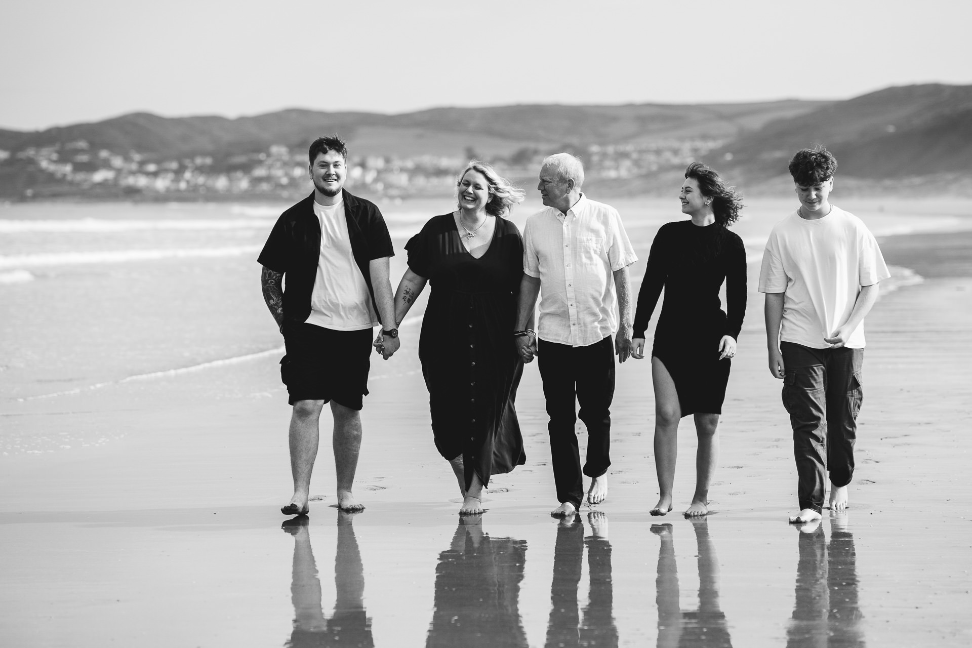 Parents with three adult children walking on the beach together at Putsborough in North Devon