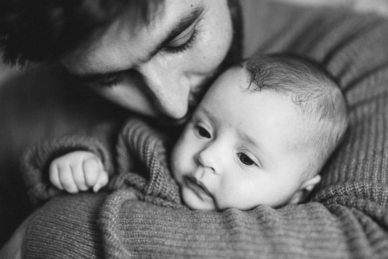 A close up of a father cuddling a baby at home