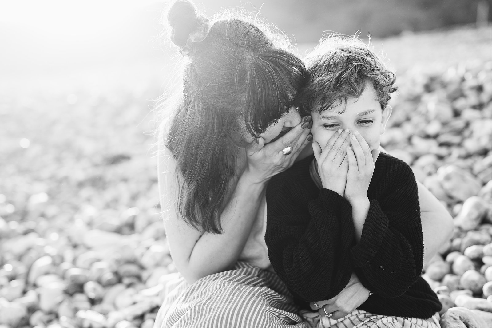 A mother and son laughing together during a family photography session on the beach in Lyme Regis