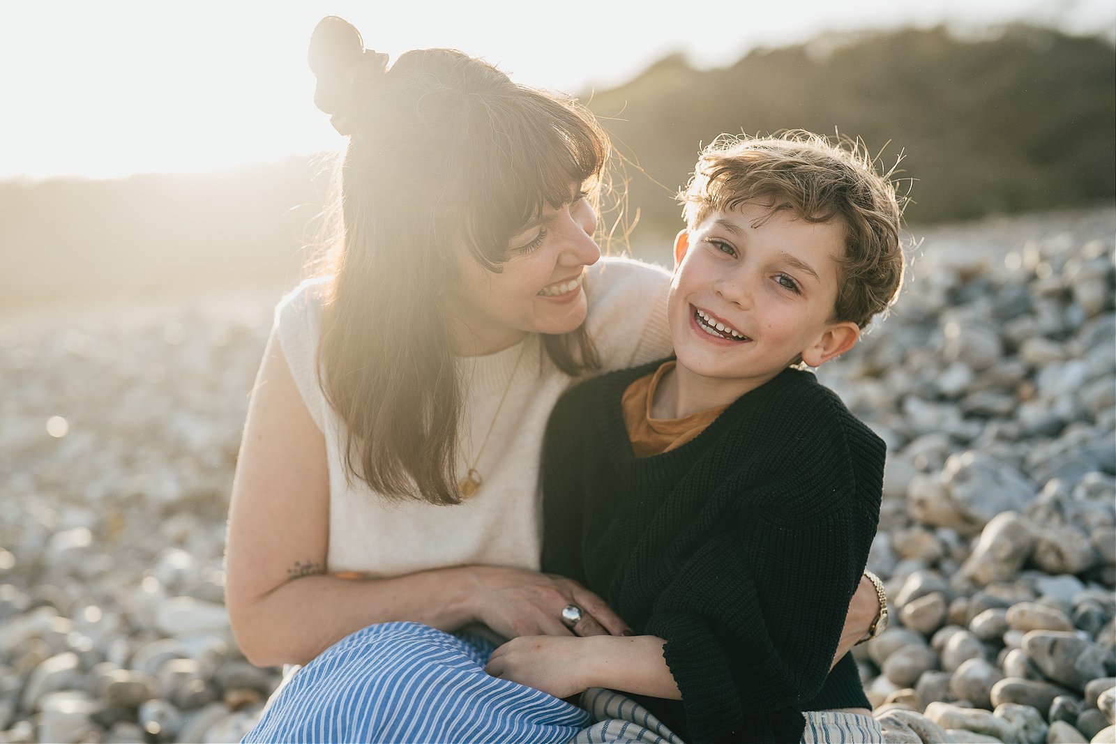 A mother and son laughing together during a family photography session on the beach in Lyme Regis