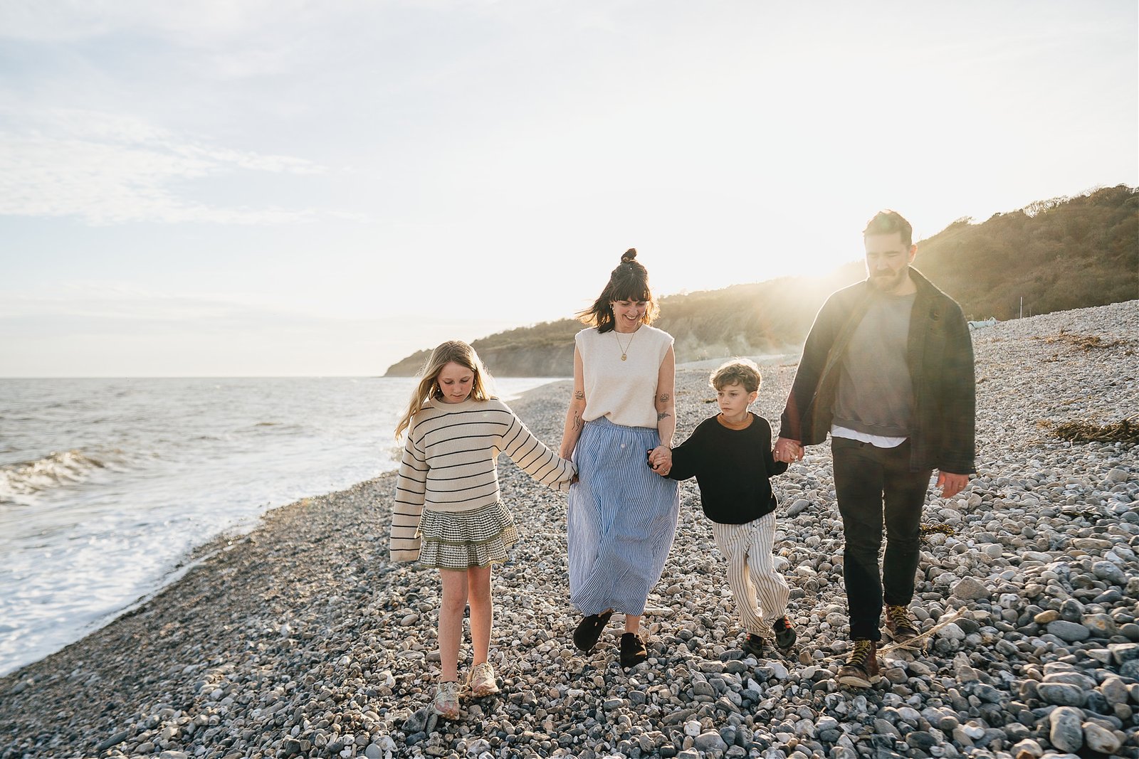 A family walking across Monmouth beach during a family photo session with Helen Lisk Photography