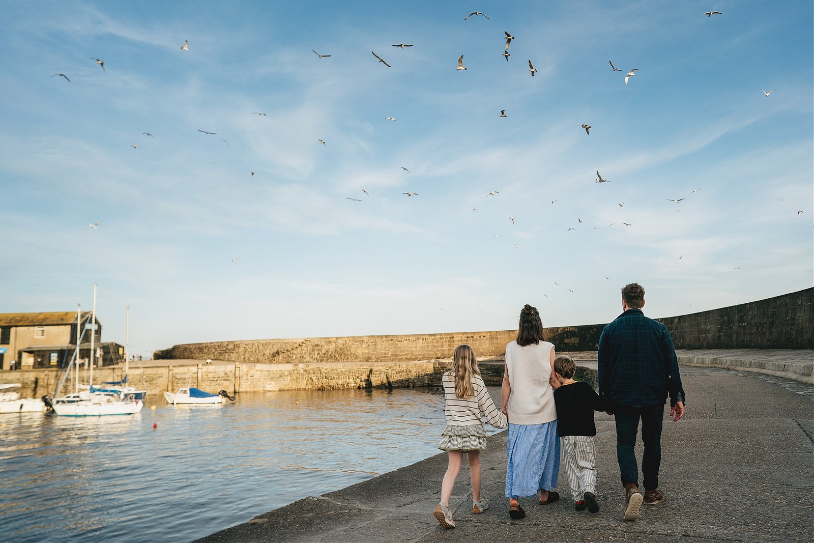 A family walking along the Cobb during a family photo session with Helen Lisk Photography