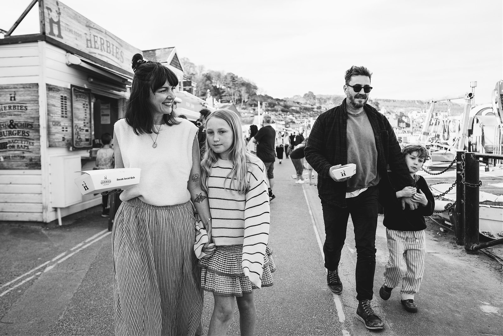 A family walking together with fish & chips along the sea front at Lyme Regis